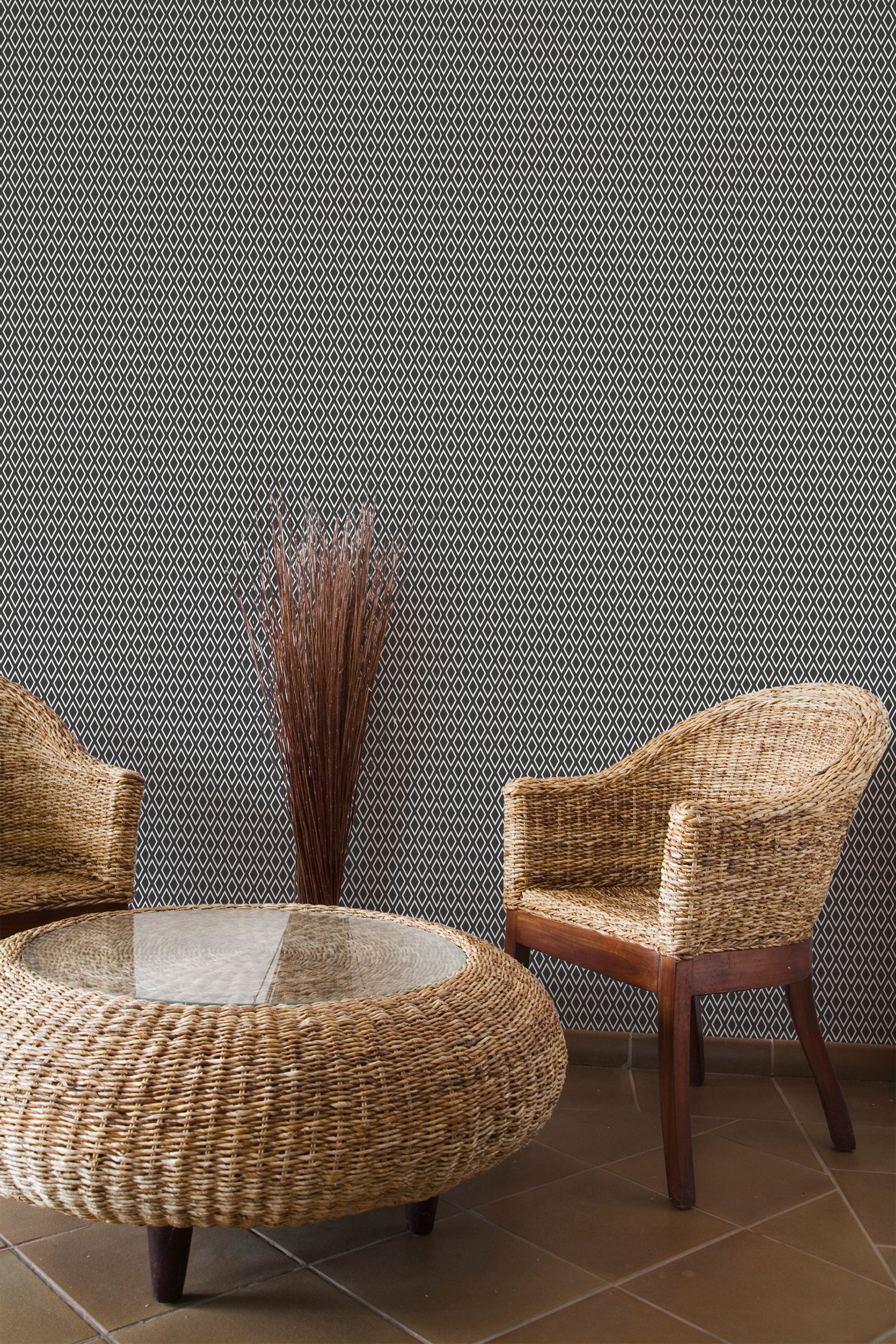 Self-adhesive wallpaper with a Harlequin design in a geometric pattern of black and white diamonds, providing a stylish and modern backdrop in a room with wicker furniture and a glass-top table.