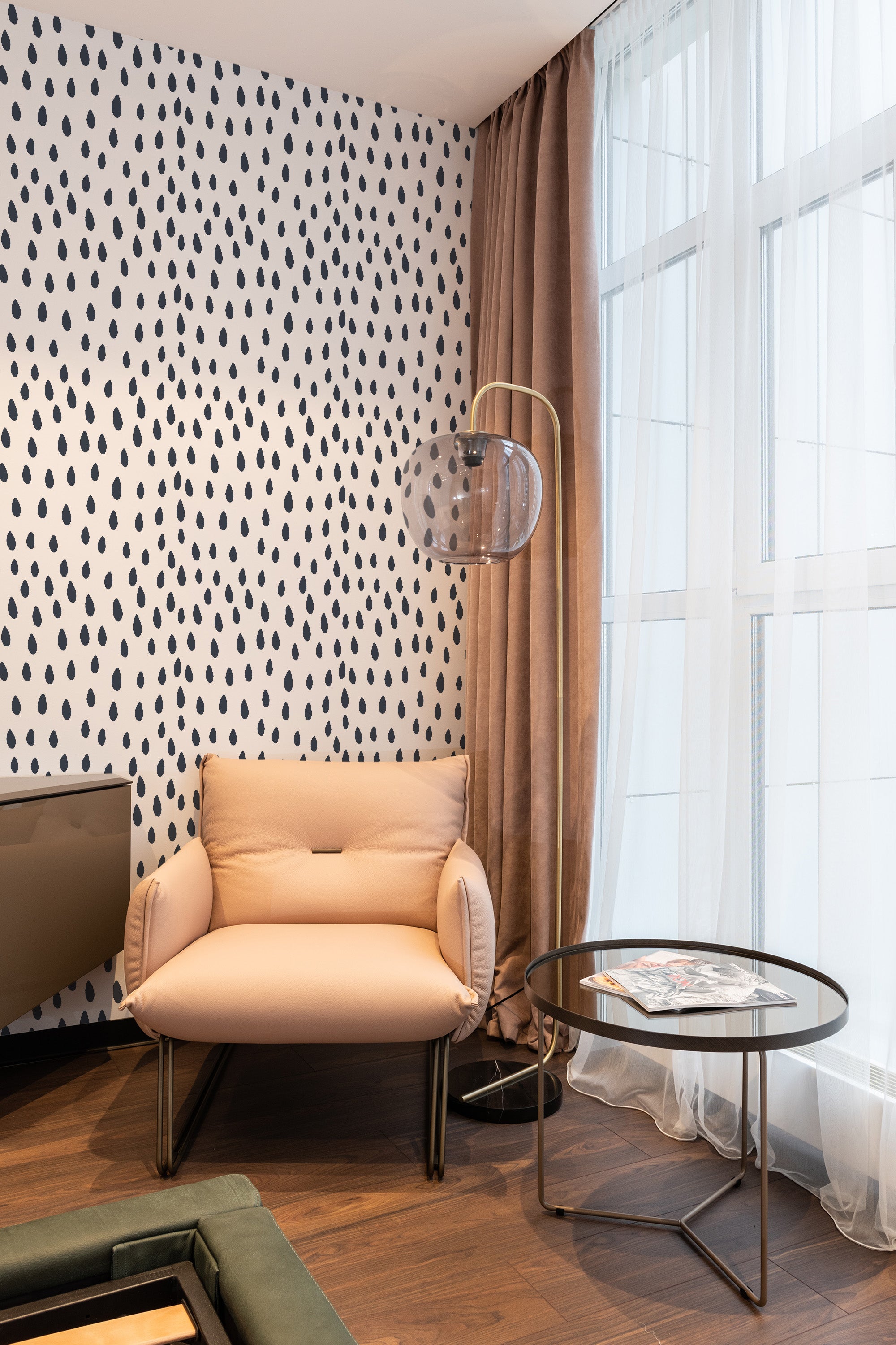 Room with light-colored walls adorned with a 'Seamless rain drops' wallpaper pattern, characterized by black raindrop shapes on a white background, providing a subtle yet elegant design element that complements the modern furniture and decor, framed by soft natural light from large windows. Traditional wallpaper.