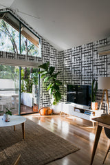 Room with a gray and white wallpaper design featuring abstract brush lines, resembling a grid-like pattern, covering the wall. Traditional wallpaper.