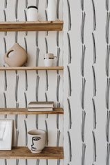 Self-adhesive wallpaper with vertical brush lines forming irregular black strokes against a white background, adding a modern artistic touch to the room.