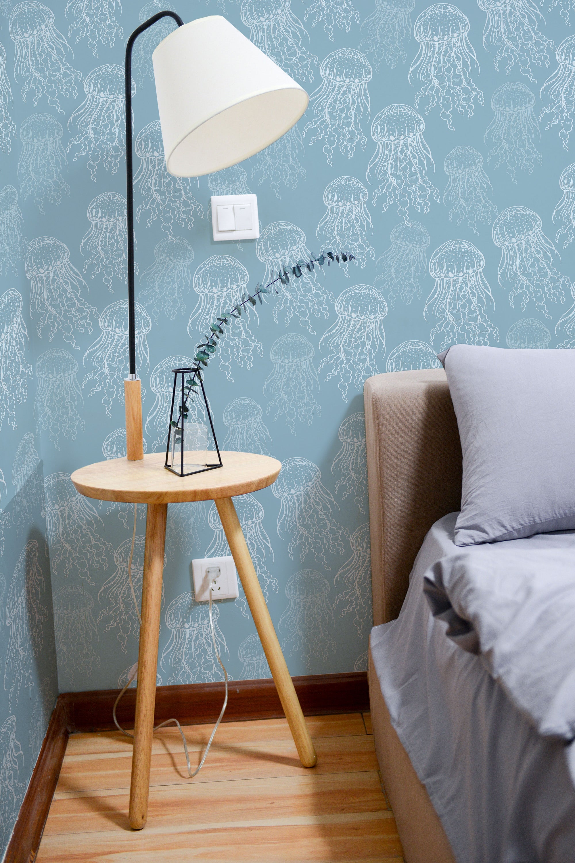 Self-adhesive wallpaper with a subtle jellyfish design on a muted blue background, adding a marine-inspired, calming touch to the room.