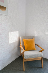 The wallpaper design named Sprinkles has a pattern of small, scattered elongated dashes on a light background, creating a minimalist and playful texture, traditional wallpaper.