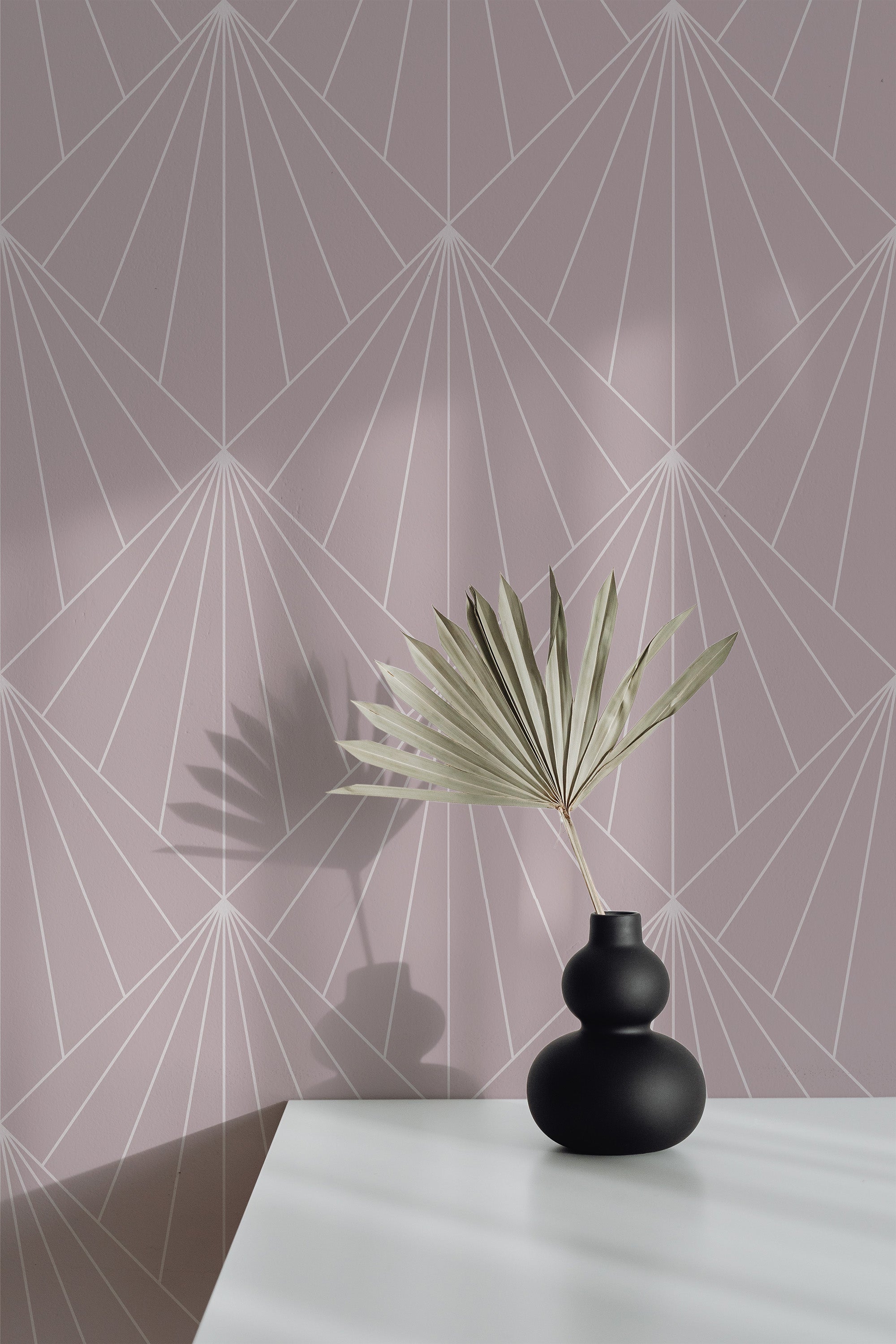 Self-adhesive wallpaper with an Art Deco geometric design with intersecting lines forming fan-like and diamond shapes against a soft mauve background.