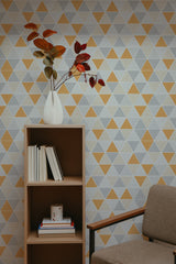 Self-adhesive wallpaper with a triangular geometric pattern in shades of yellow, gray, and white, creating a modern and stylish look in the room.