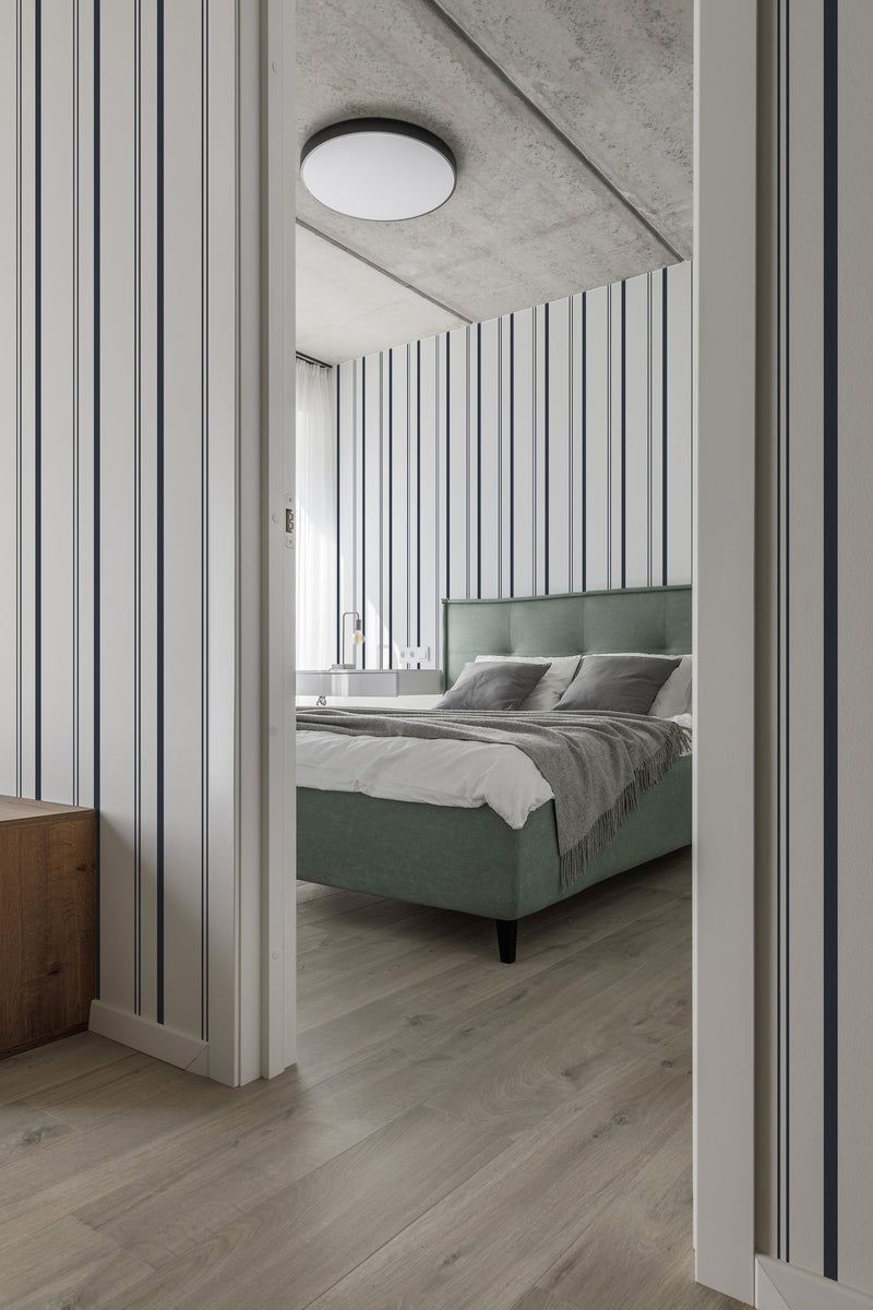 Room with light-colored walls adorned with fabric stripe pattern wallpaper featuring vertical navy and white stripes, creating a classic look in the bedroom. Traditional wallpaper.