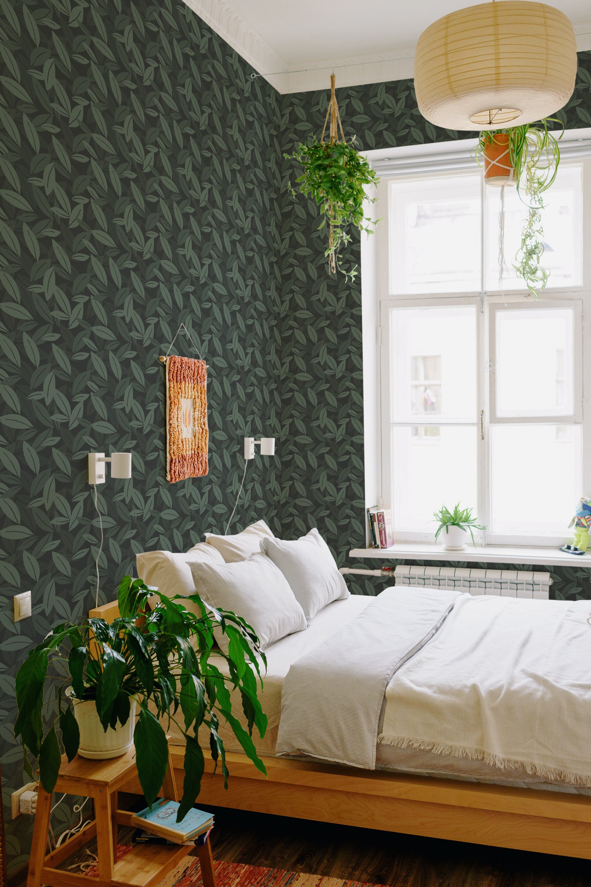 A room with walls covered in a bold green leaf pattern wallpaper with a repeating design, adding a touch of nature to the space. The leaves are dark green with a subtle texture and coverage on a darker background. The timeless design brings a fresh yet elegant feel to the room, enhancing the overall cozy and inviting atmosphere. Traditional wallpaper.