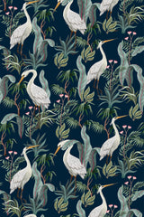 Elegant wallpaper design with white cranes standing among lush green foliage and delicate pink flowers on a dark blue background. Peel and stick removable wallpaper.