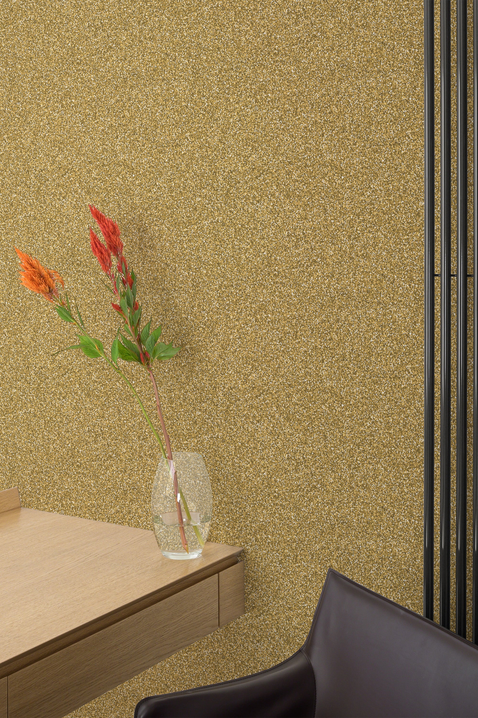 Self-adhesive wallpaper with a golden glitter design, creating a shimmering and luxurious backdrop in the room. The textured finish adds depth and elegance, complementing the minimalistic decor, including a sleek wooden surface and a vase with vibrant flowers.