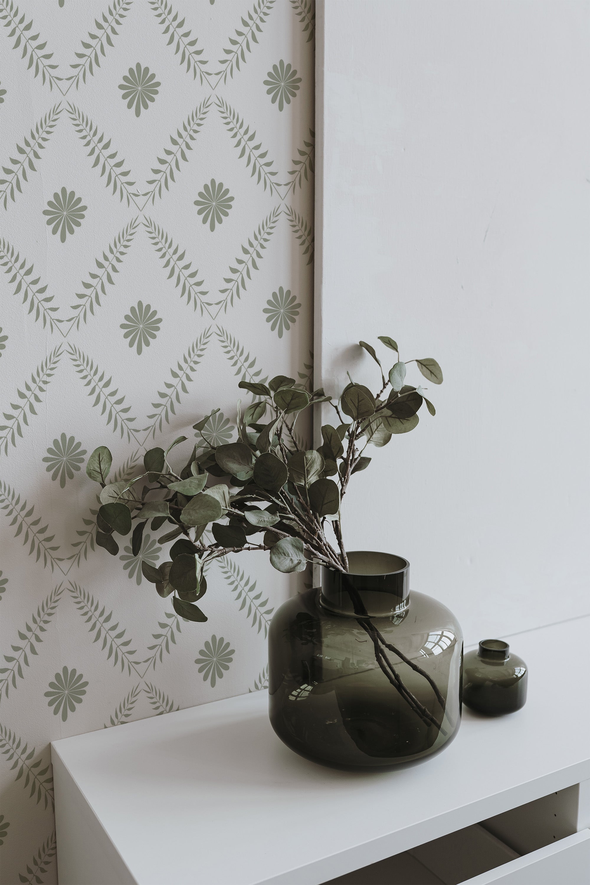 Self-adhesive wallpaper with a Leaf Tile design in green and white, arranged in a diamond pattern with alternating floral and leafy motifs.