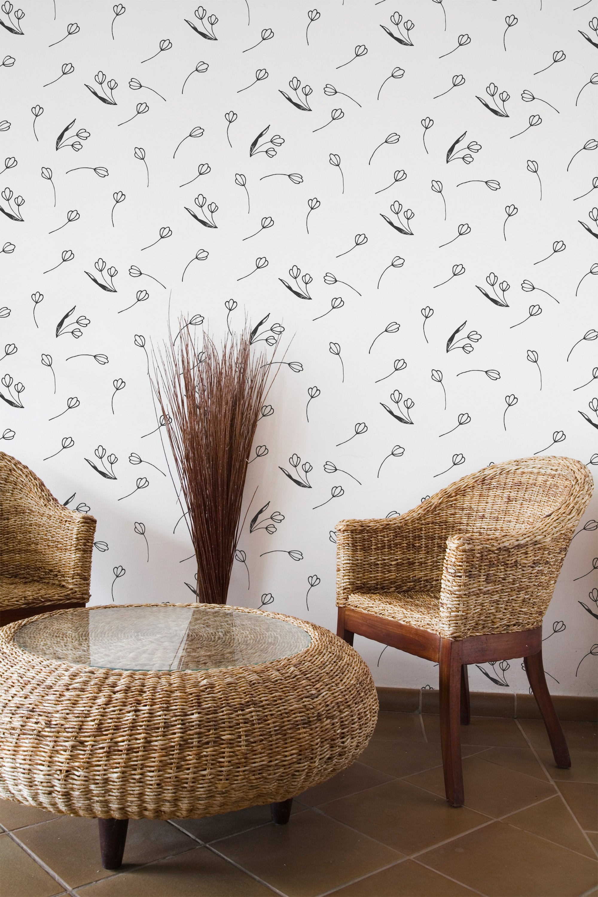 Self-adhesive wallpaper with a minimalist floral pattern of delicate, simple black line-drawn flowers on a white background, perfectly complements the natural wicker furniture and glass-topped table in the room.