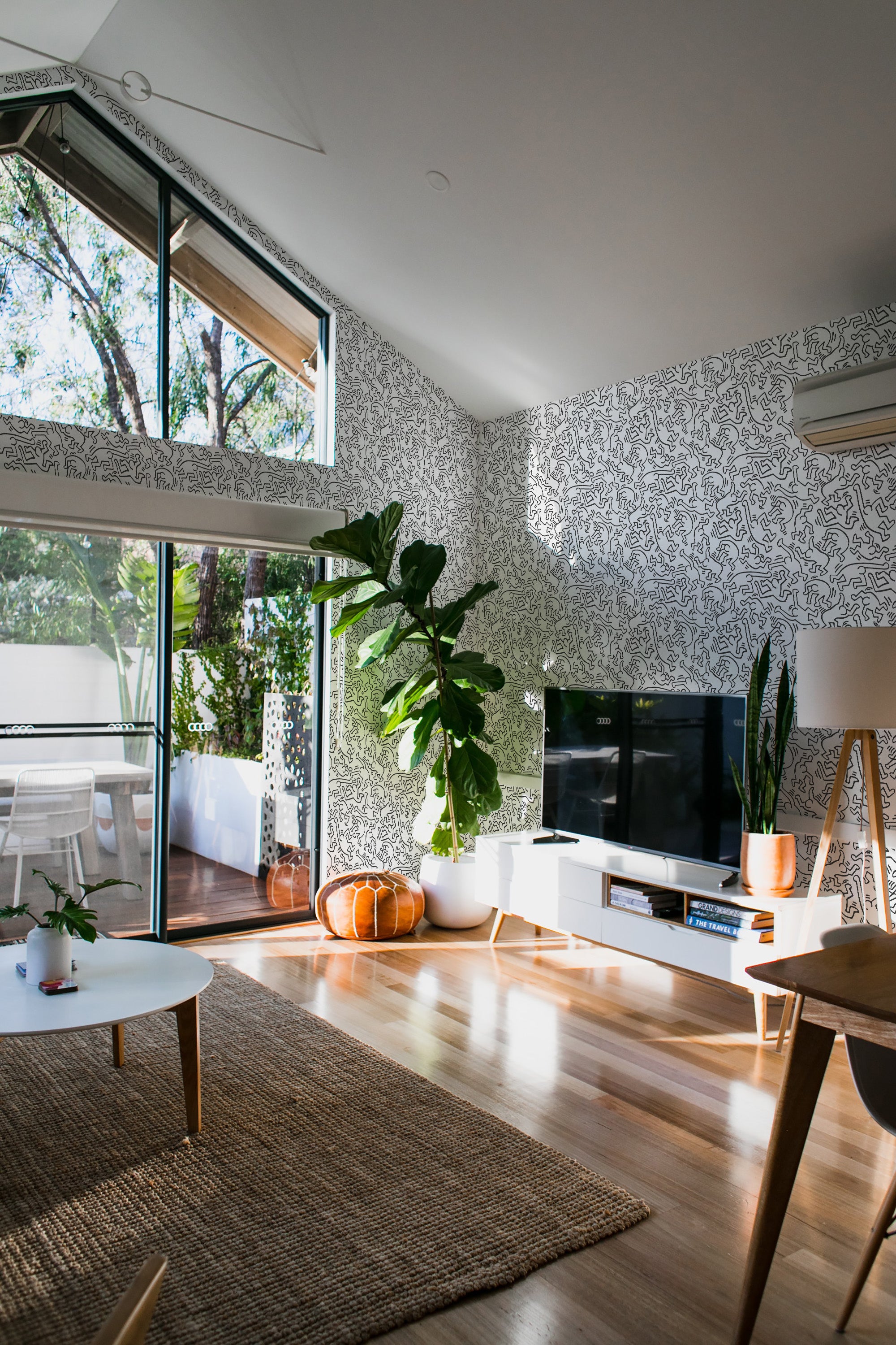 The room has wallpaper adorned with a playful doodle design featuring stick figures scattered across the wall, adding a whimsical touch to the space. The wallpaper is a traditional wallpaper.