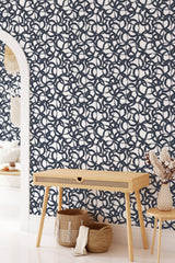  Wallpaper with a bold, repeating navy circular pattern on a white background, creating a striking modern look in a traditionally styled room with light wooden furniture. Traditional wallpaper.