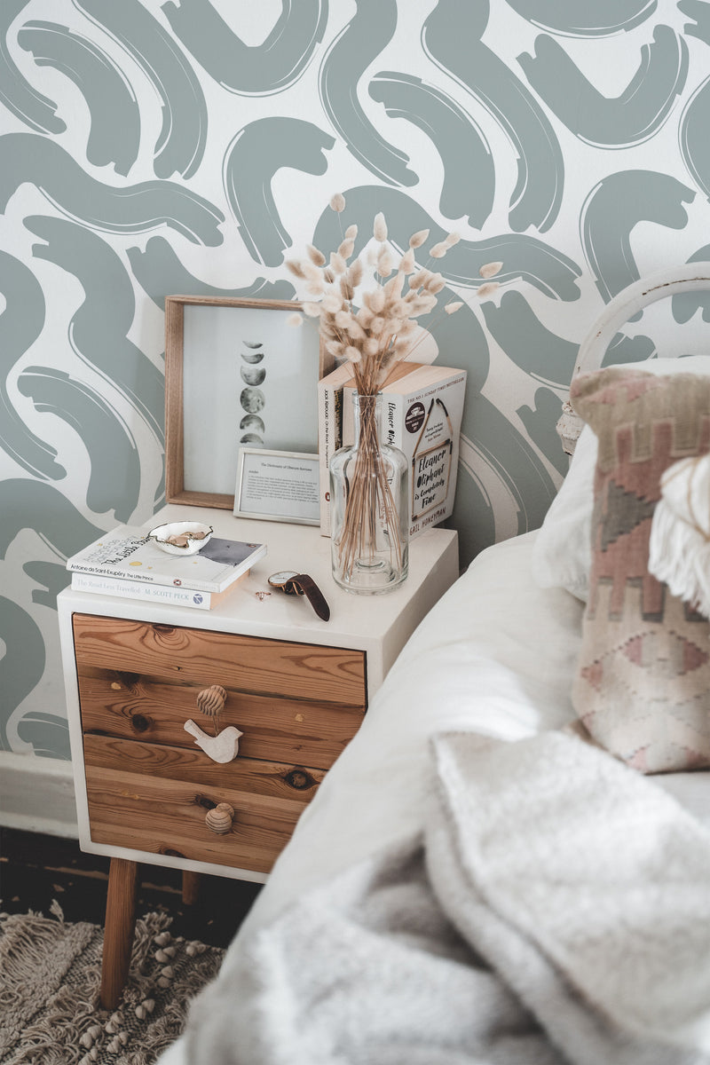 Self-adhesive wallpaper with a Big Brush Lines design in soft gray and white abstract curved strokes creating a modern, artistic backdrop in a cozy bedroom.