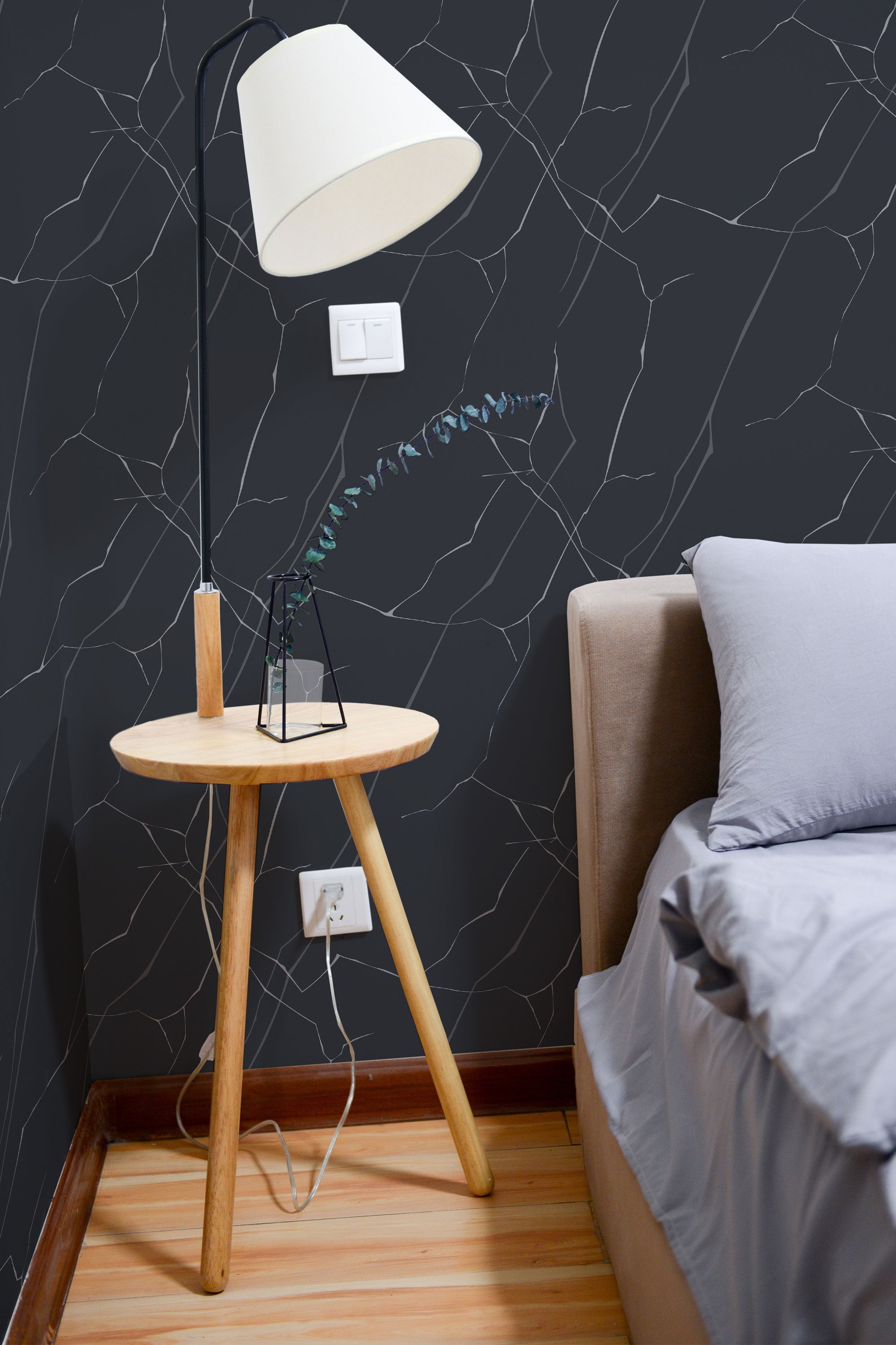 Self-adhesive black blue marble wallpaper with intricate white veining on a room's wall behind a wooden side table and sofa, complementing the modern decor.