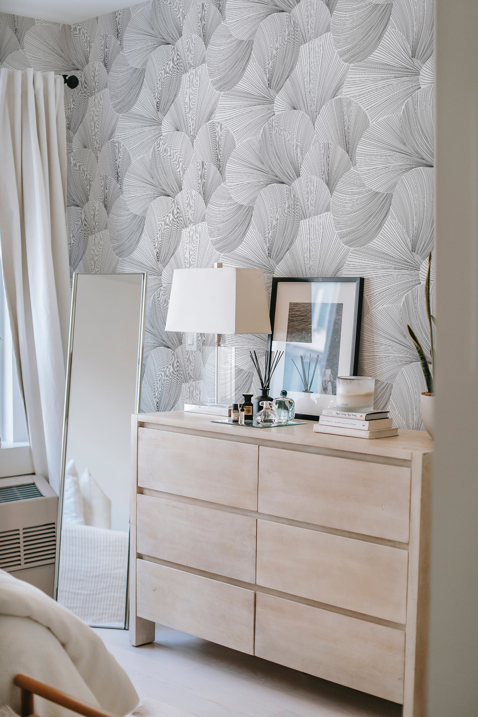 A room with a wall covered in seamless line art wallpaper with a leaf pattern in a grayscale color scheme, adding an artistic touch to the space. It's a blend of nature-inspired design and traditional wallpaper.