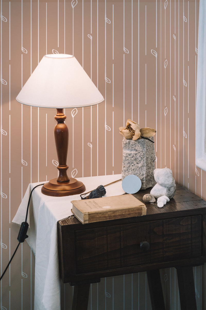 Self-adhesive classic striped wallpaper with beige background and white vertical lines, highlighted by parallel tan and white dashed lines, in a room with a wooden desk and lamp.