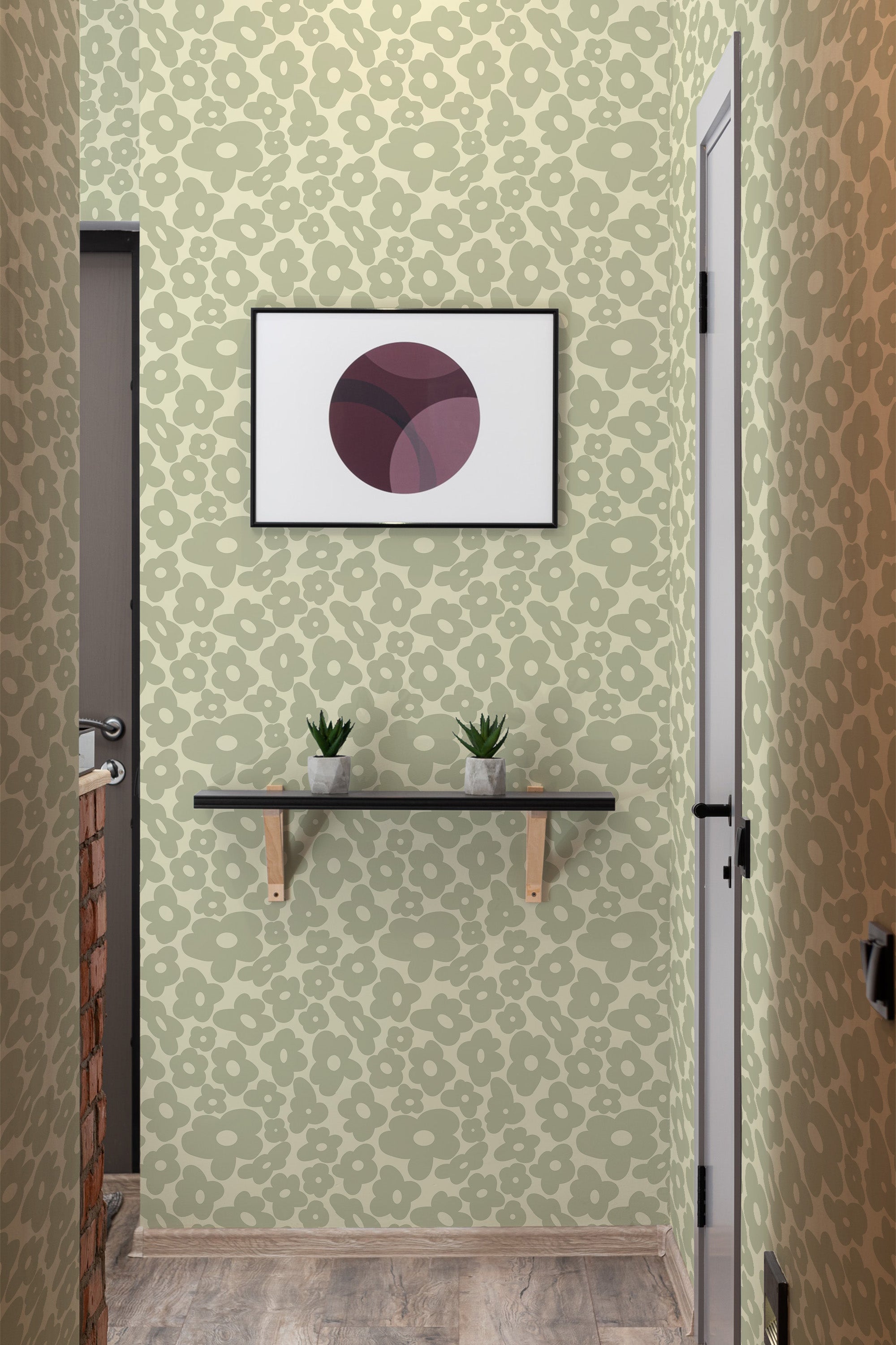 A room with sage green retro wallpaper with a speckled pattern, a framed artwork above a wooden shelf with two plants, and a traditional wallpaper vibe.