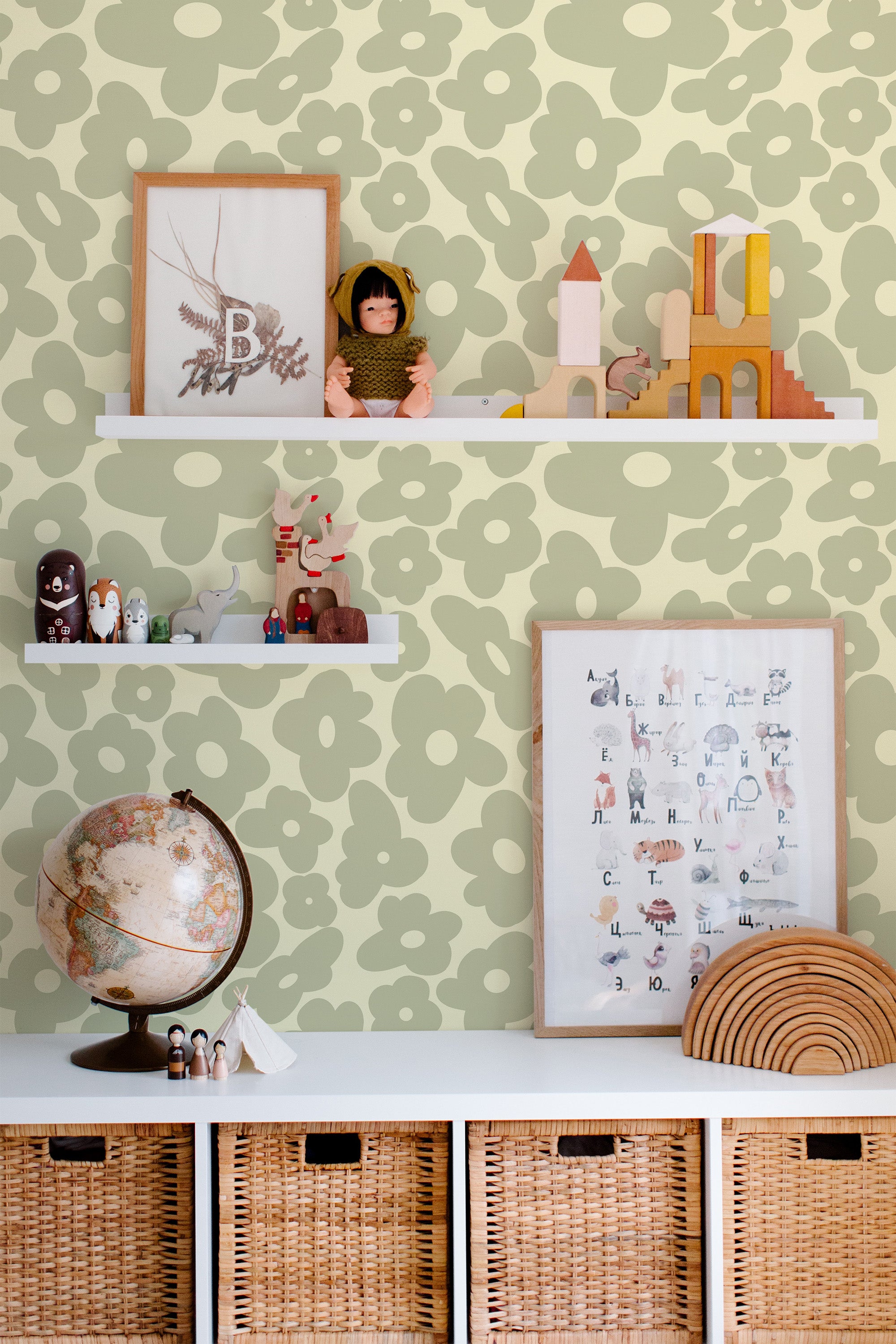 Self-adhesive sage green retro wallpaper with large flower patterns in a child's room with decorative items and toys on shelves.