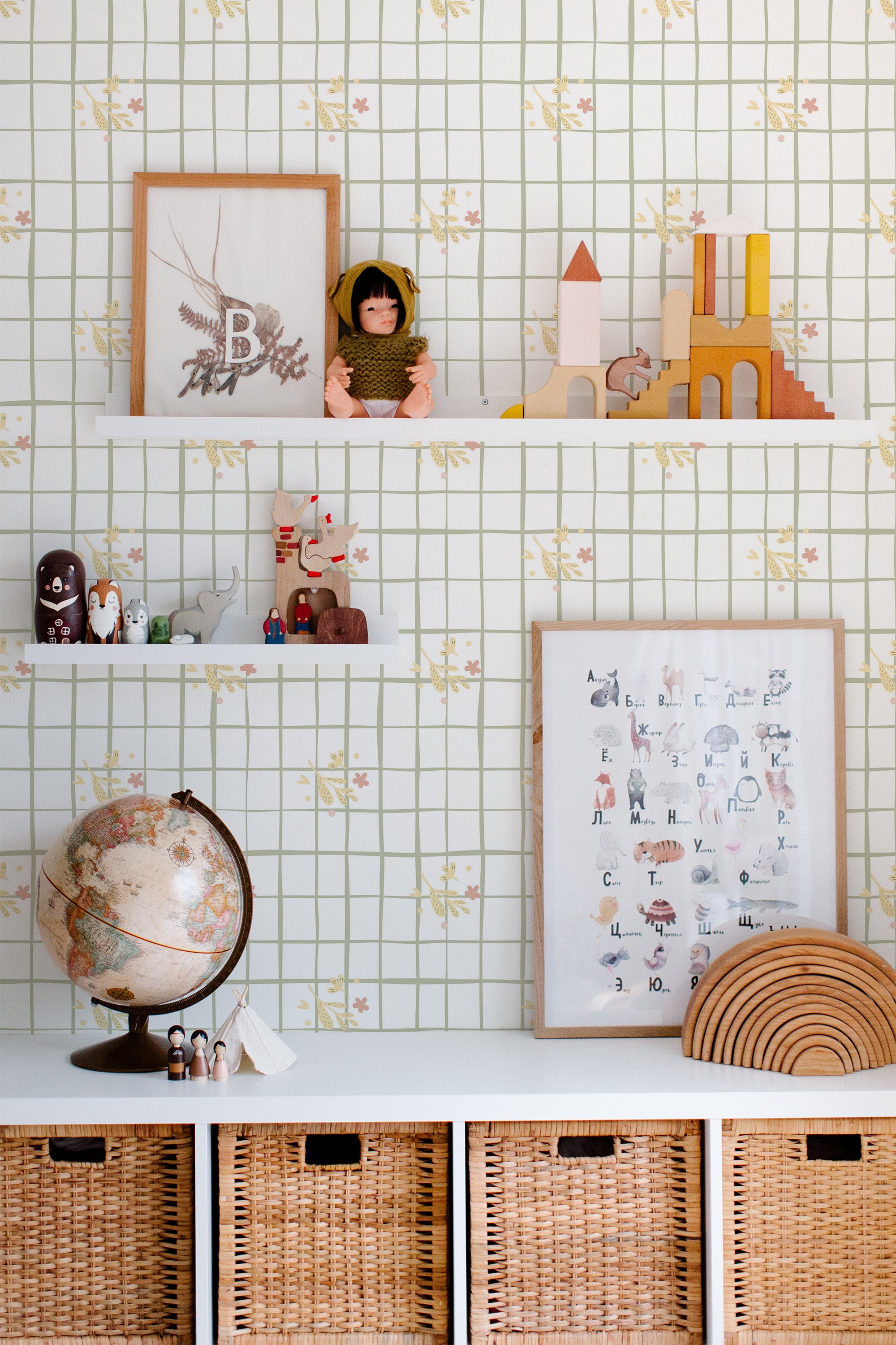 Self-adhesive wallpaper with a grid design and small floral motifs in a kitchen, accented by decorative objects and children's toys on shelving.