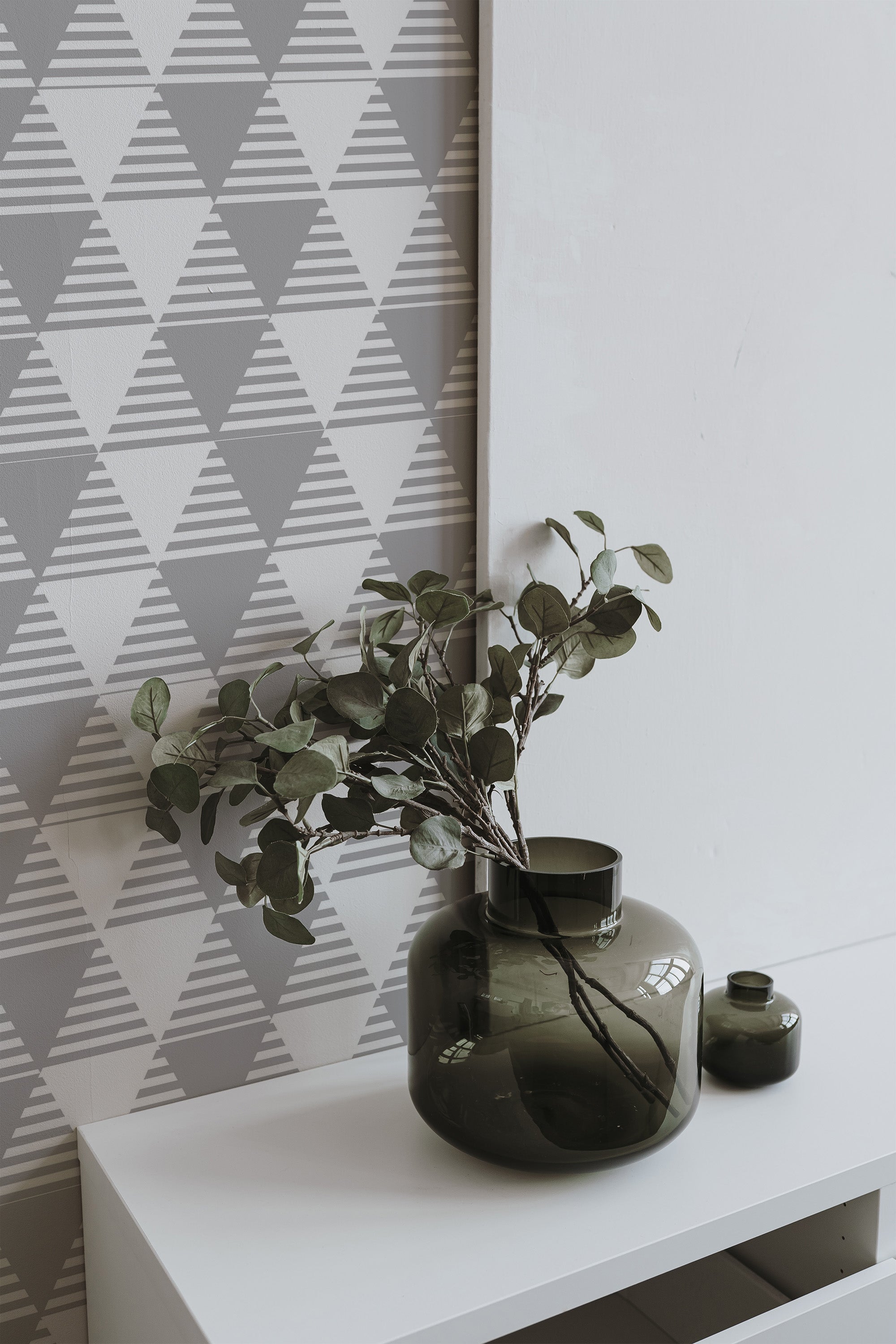 Self-adhesive wallpaper with a geometric pattern of gray and white triangles, adding a modern touch to the room decor.