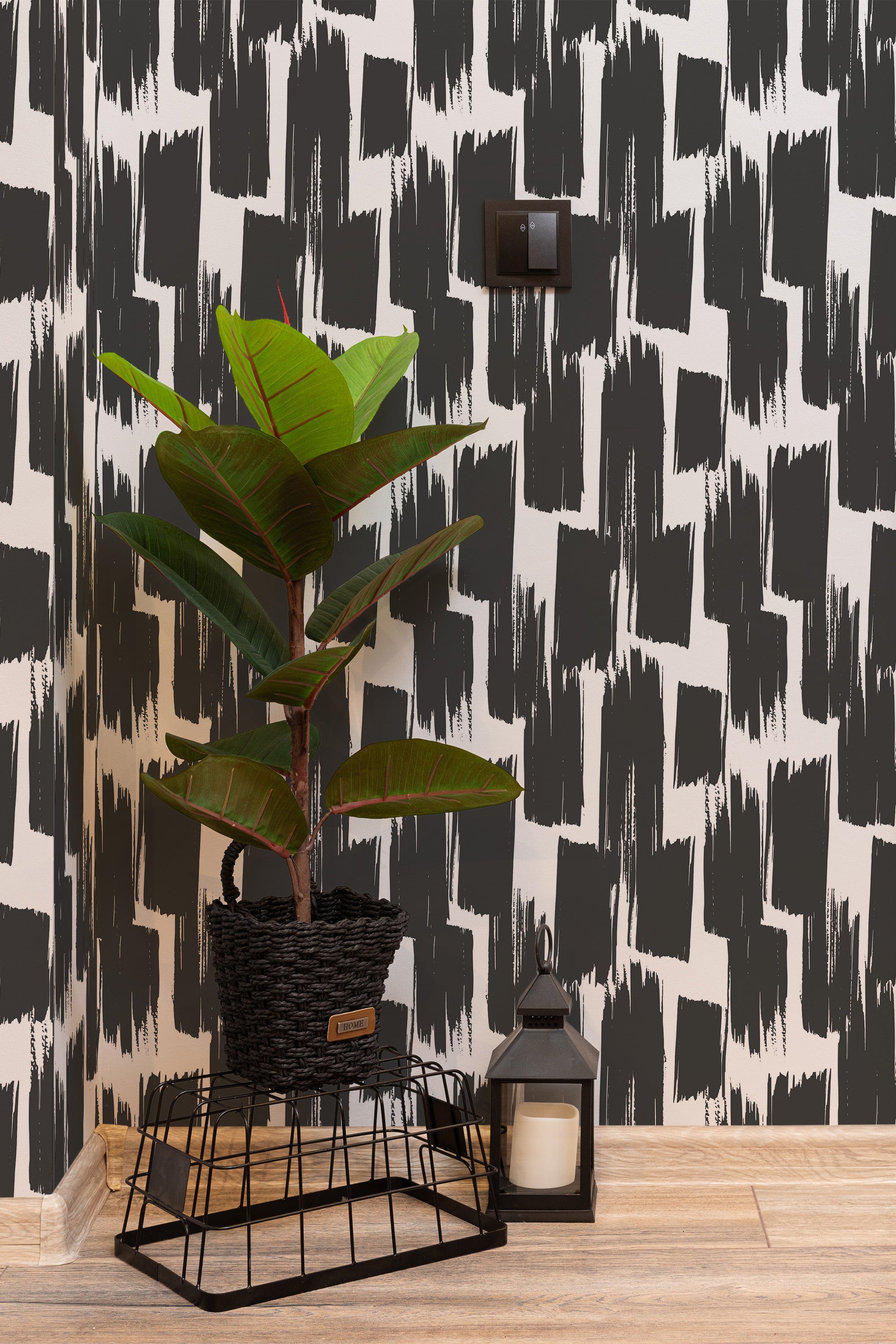 Self-adhesive wallpaper with a bold black and white brushstroke pattern, paired with a potted plant and lantern on a wooden floor.
