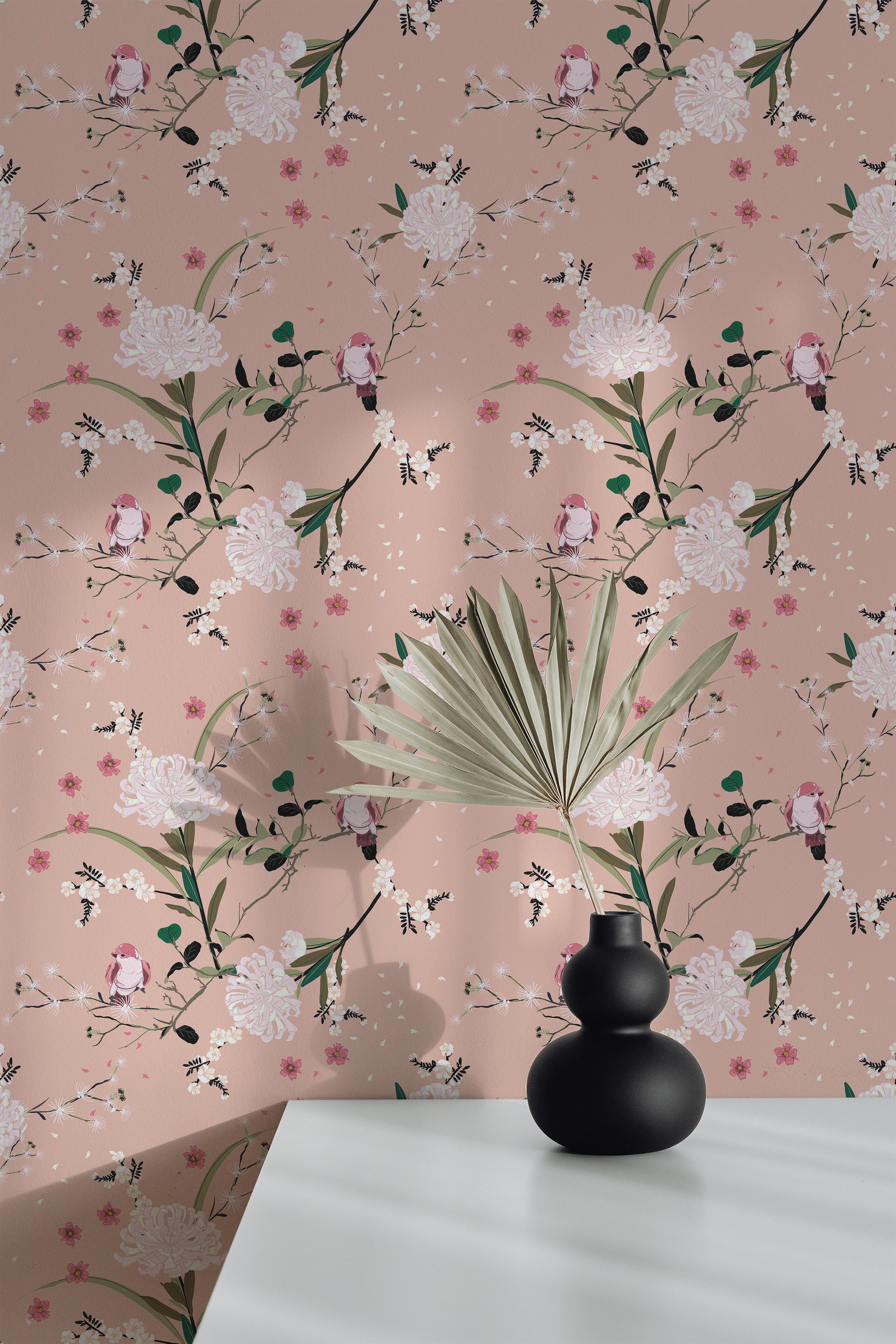 Self-adhesive wallpaper with a Spring bird design, including floral patterns and birds on a pink background, with white flowers and green leaves. A black vase with foliage sits on a white surface in front.