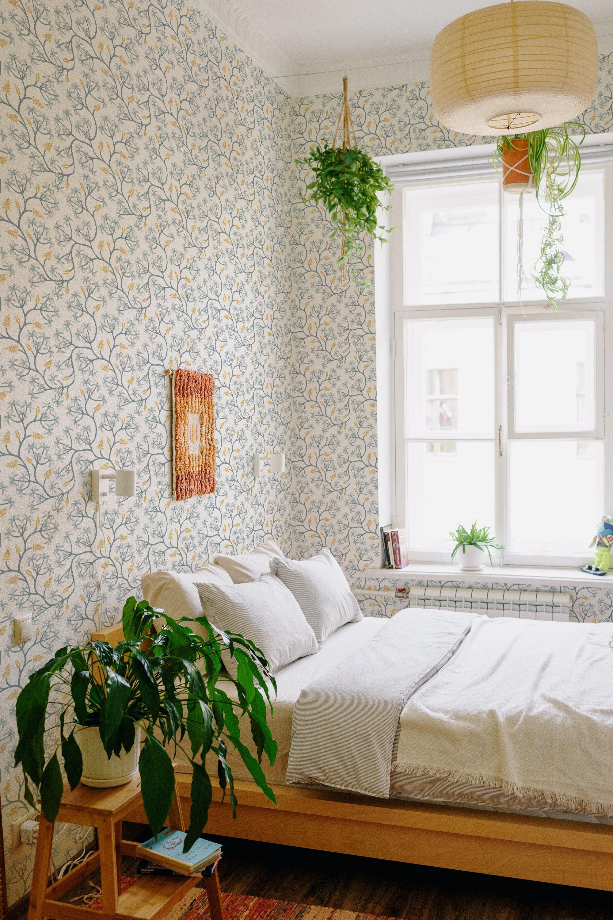A bedroom with blue seamless floral wallpaper with delicate flowers and leaves patterns on a light background, giving the space a tranquil and traditional wallpaper aesthetic.