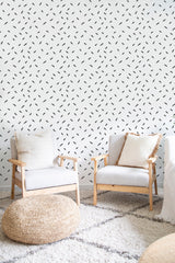 A room with Mini brush stroke wallpaper, comprising small dark brush strokes arranged in a random pattern on a light background, giving a modern twist to traditional wallpaper.