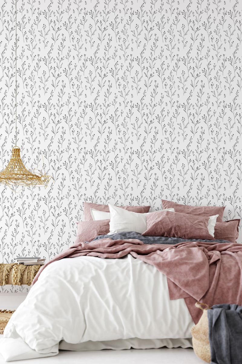 A bedroom with a wall covered in minimalist floral wallpaper, with simple, monochrome leafy branch patterns, providing an elegant backdrop to a bed with pink and white bedding, traditional wallpaper.