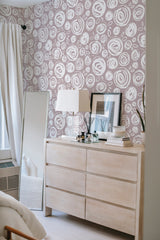 A room with a wall covered in Brush rose wallpaper, displaying swirled rose patterns in a monochromatic style, adding a touch of elegance to the space as traditional wallpaper.