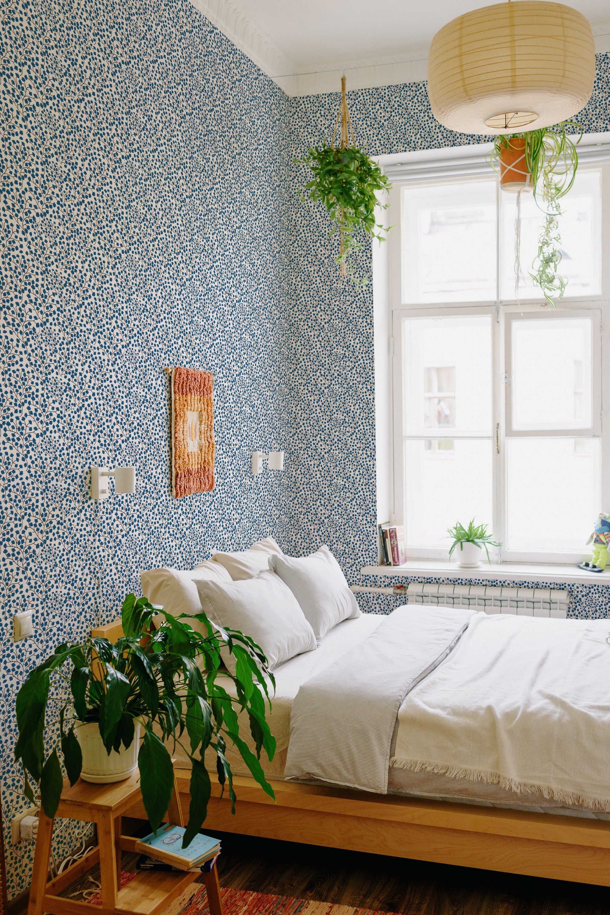 A room with walls adorned in Tiny blue floral wallpaper, including small blue flowers scattered on a white background, giving the space a fresh and traditional wallpaper feel.