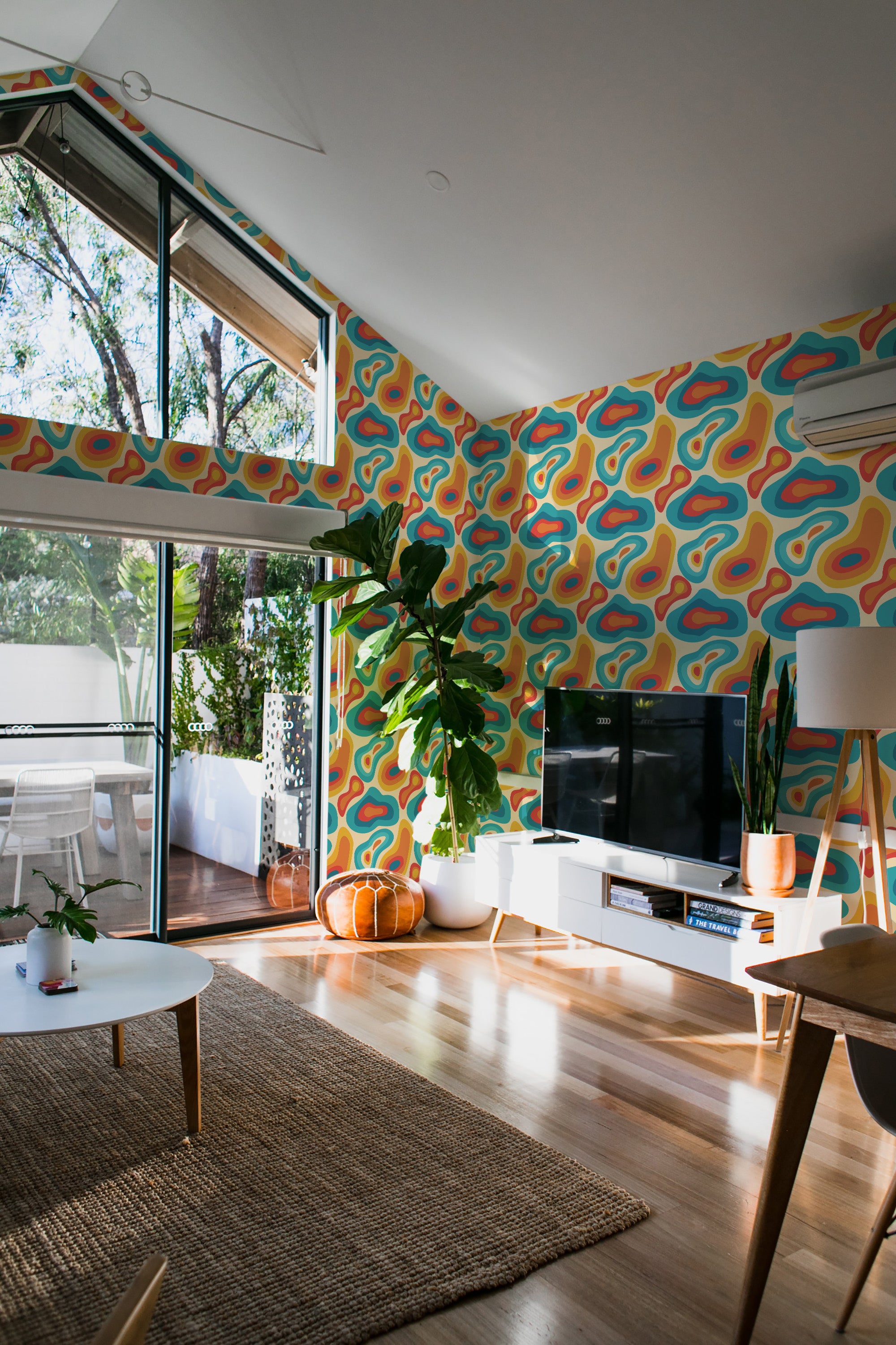 A bright room with a wall covered in colorful retro shapes wallpaper in curved, abstract patterns, blending orange, blue, and green hues on a light background, a traditional wallpaper.