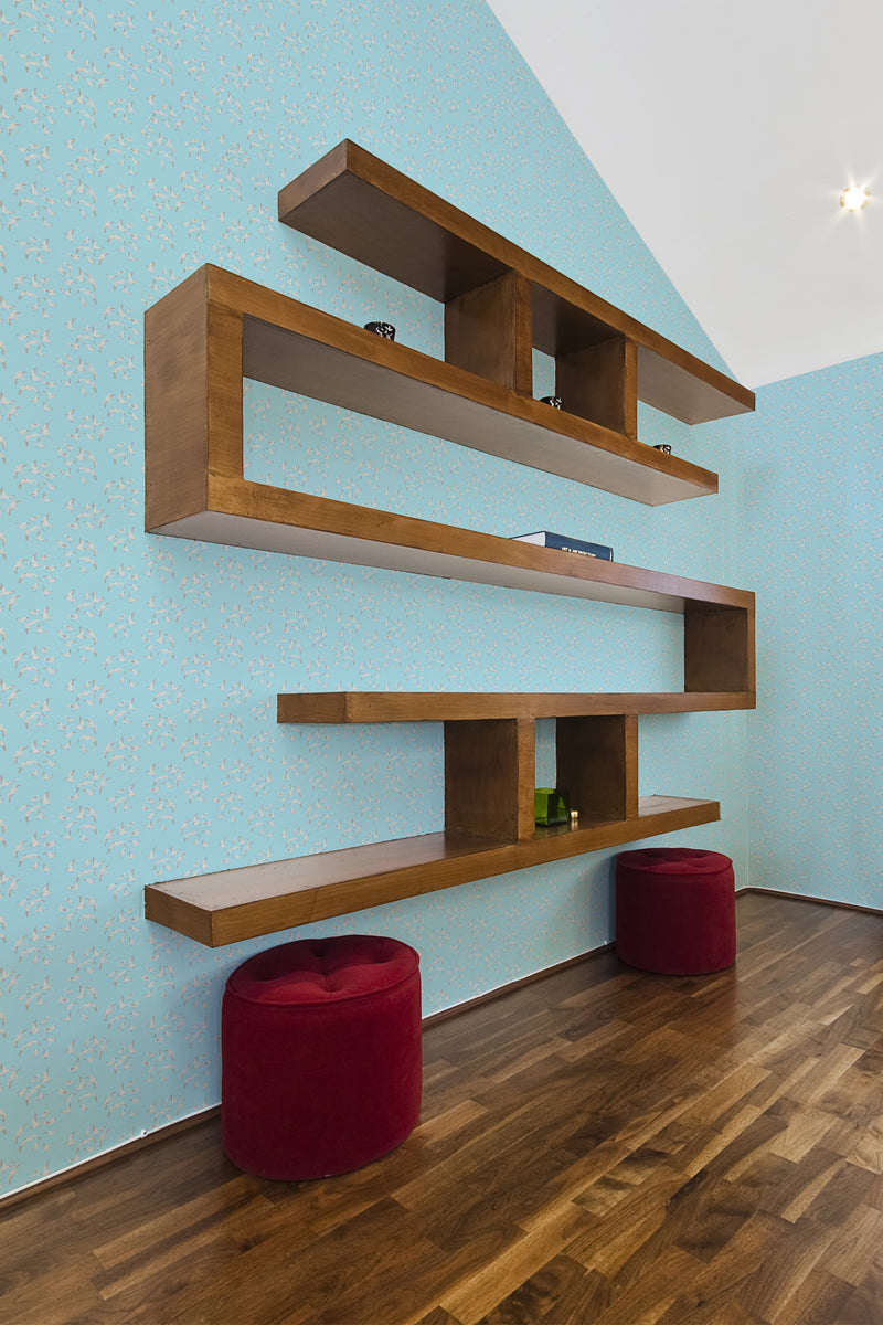 A room with light blue wallpaper adorned with small, stylized seagull patterns complemented by floating wooden shelves and two red poufs, embodying a maritime theme in traditional wallpaper.