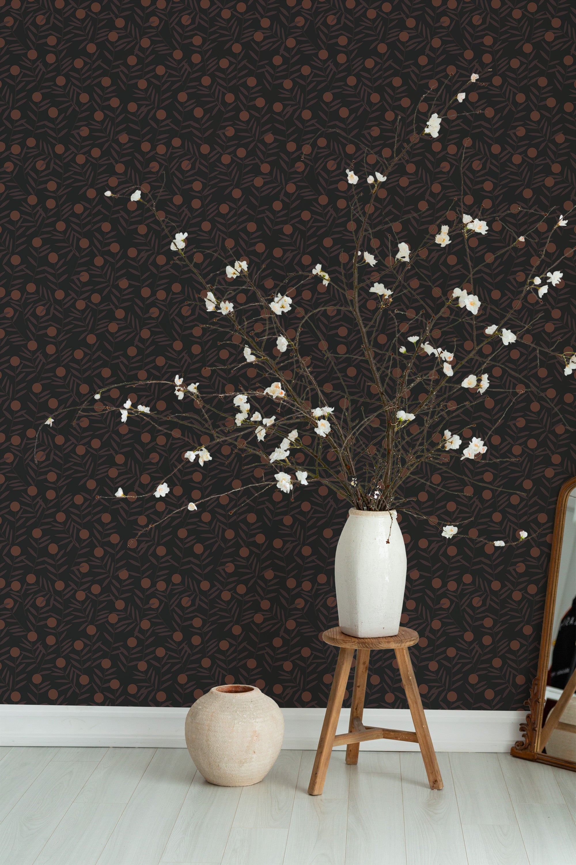 Self-adhesive Bold Citrus wallpaper pattern with intertwining orange and lemon outlines on a dark backdrop, accentuated by a vase of white blossoms on a wooden stool.