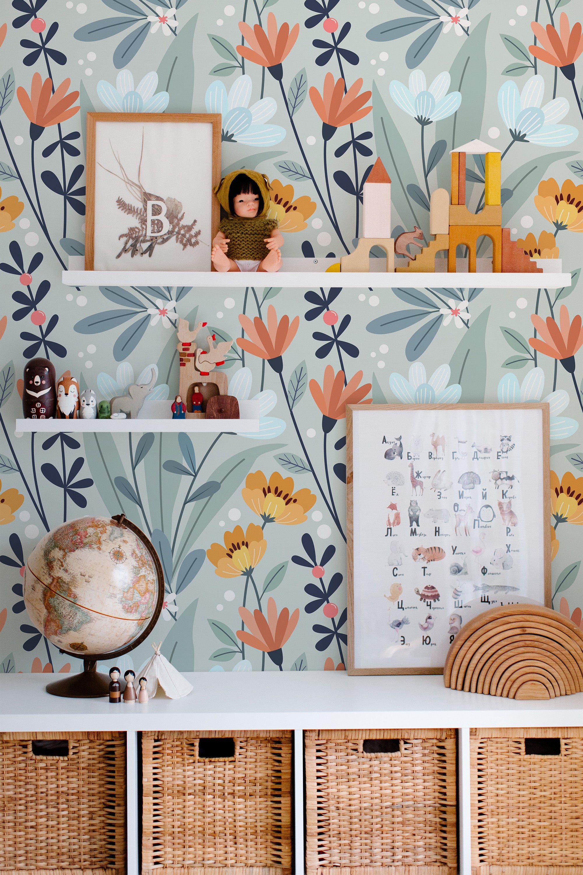 Self-adhesive wallpaper with a floral pattern in hues of blue, orange, and green, accented by shelves with toys and educational posters.