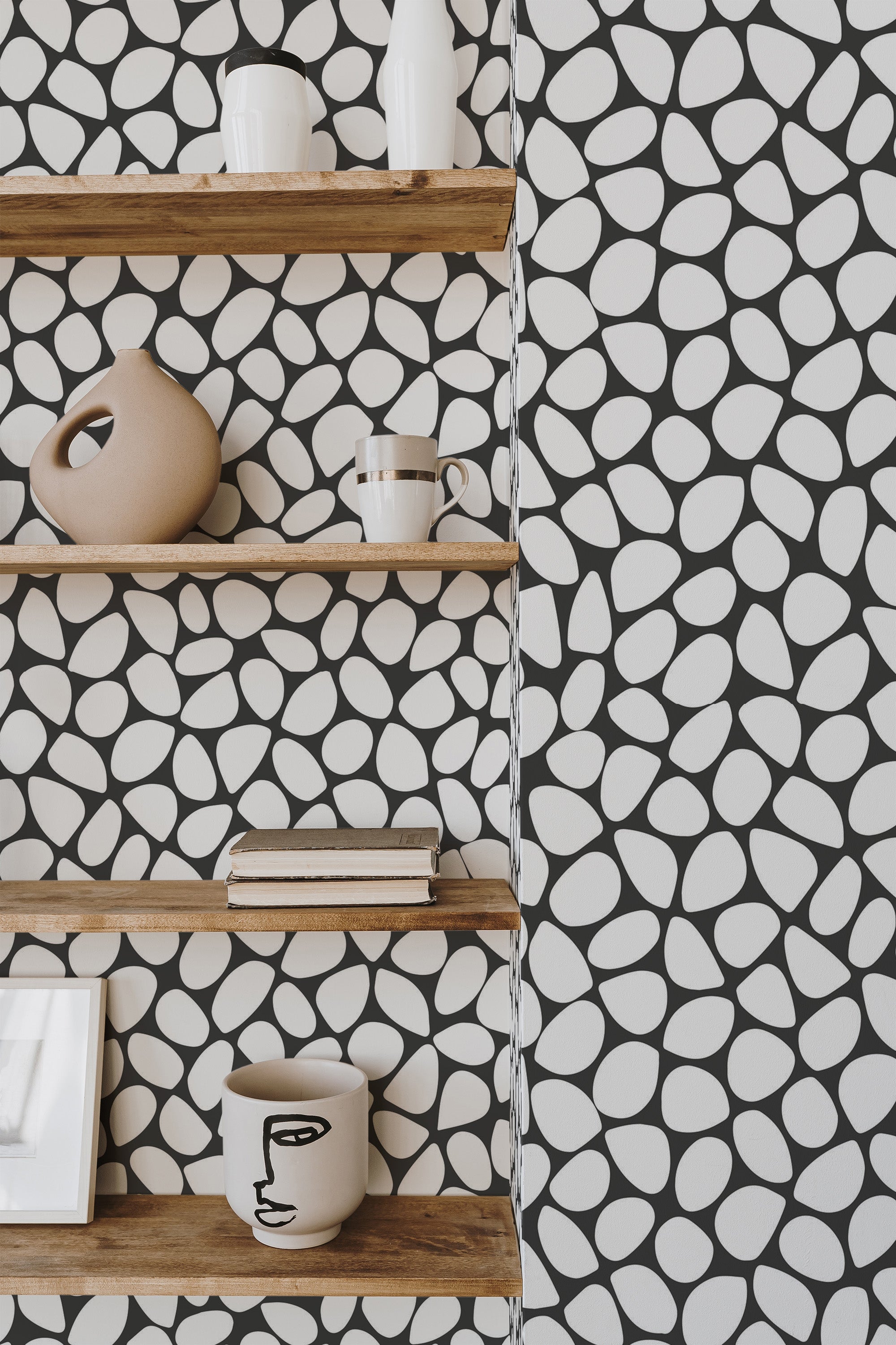 Self-adhesive wallpaper with stone dots pattern in black and white, seen behind wooden shelves with decorative items.