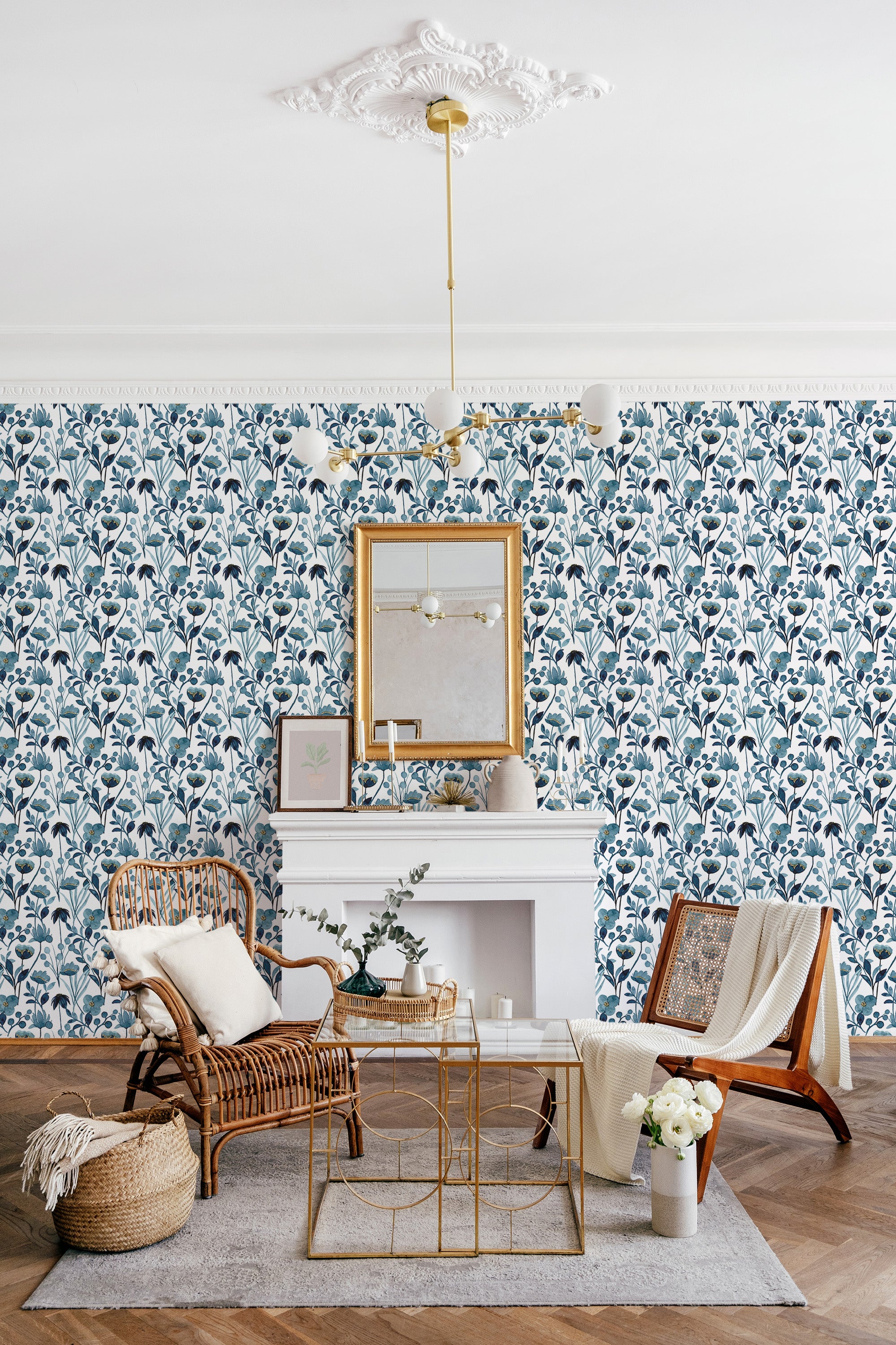 A room with blue watercolor floral wallpaper adding an elegant touch to the decor, complemented by a white mantelpiece, gold-framed mirror, and cozy furniture, embodying traditional wallpaper.