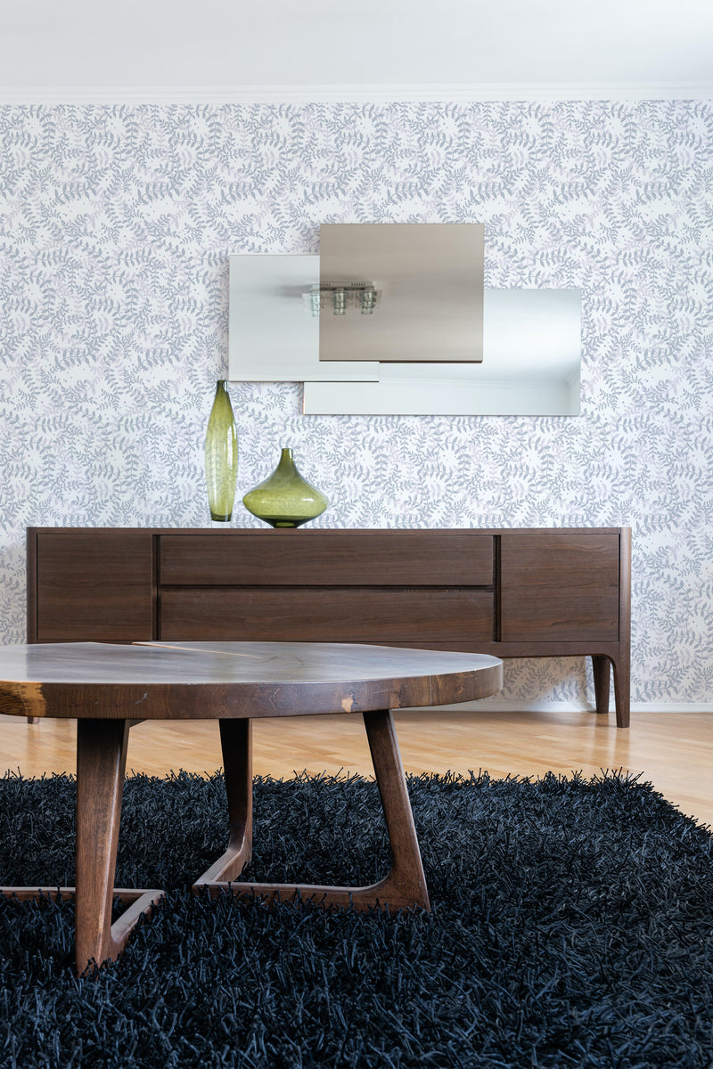 A room with Purple Leaf designed wallpaper on one wall, with subtle hues and a pattern of stylized leaves. Accented by modern furniture and a shaggy blue rug, creating a chic interior with traditional wallpaper.