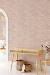 A room with wallpaper in a soft pink tone adorned with a subtle texture and linear pattern, creating a warm and inviting atmosphere. Traditional wallpaper.