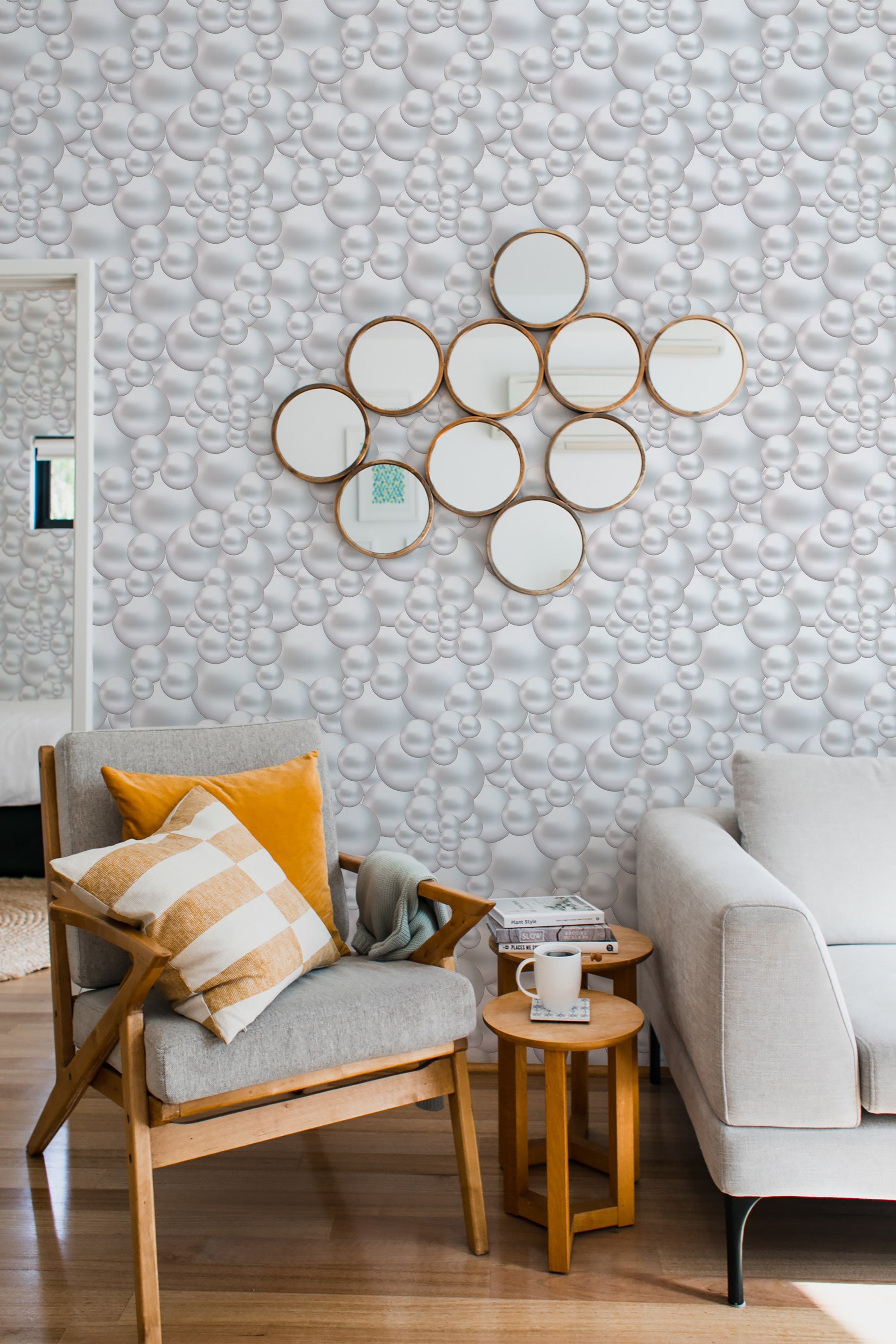 A room with wallpaper adorned in a soft grey tone with an intricate pattern of interconnected, rounded pearl-like shapes creating a subtle, textured effect. Warm wood and neutral-toned furniture complement the design, adding a cozy feel to the space. Traditional wallpaper.