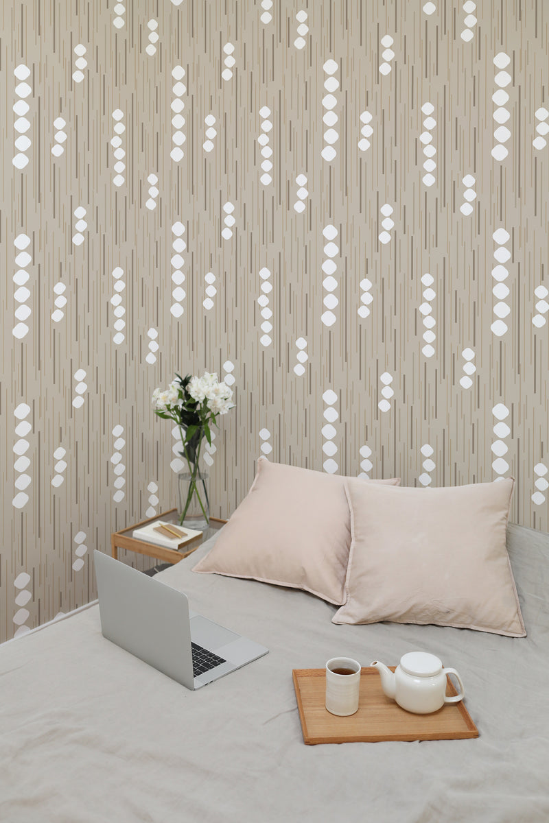 Self-adhesive wallpaper with a neutral vertical stripe pattern interspersed with abstract white dot clusters, creating a modern and minimalist look in a cozy room setting.