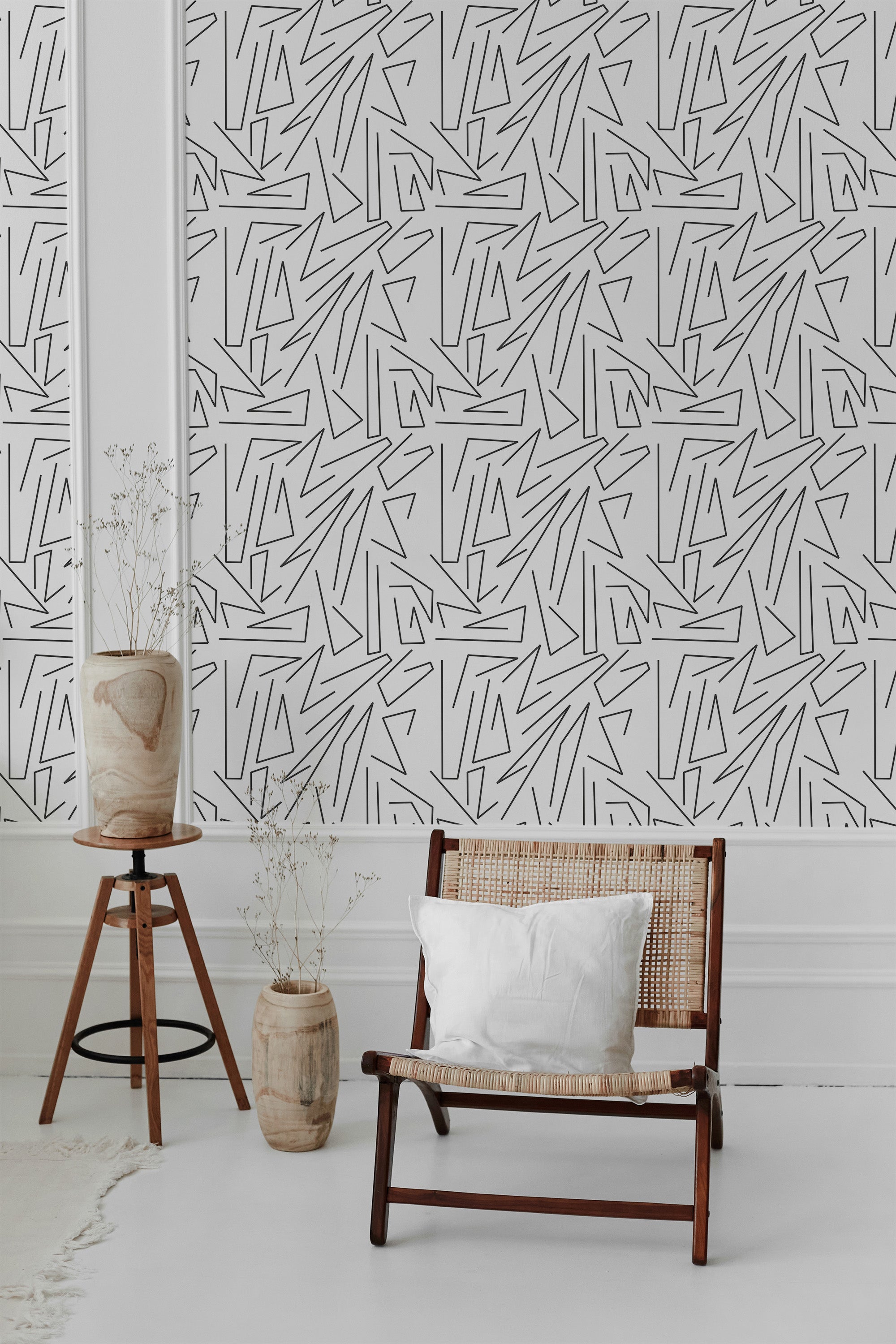 Black geometric lines form an intricate, abstract pattern on white, creating a modern, minimalist aesthetic on traditional wallpaper.