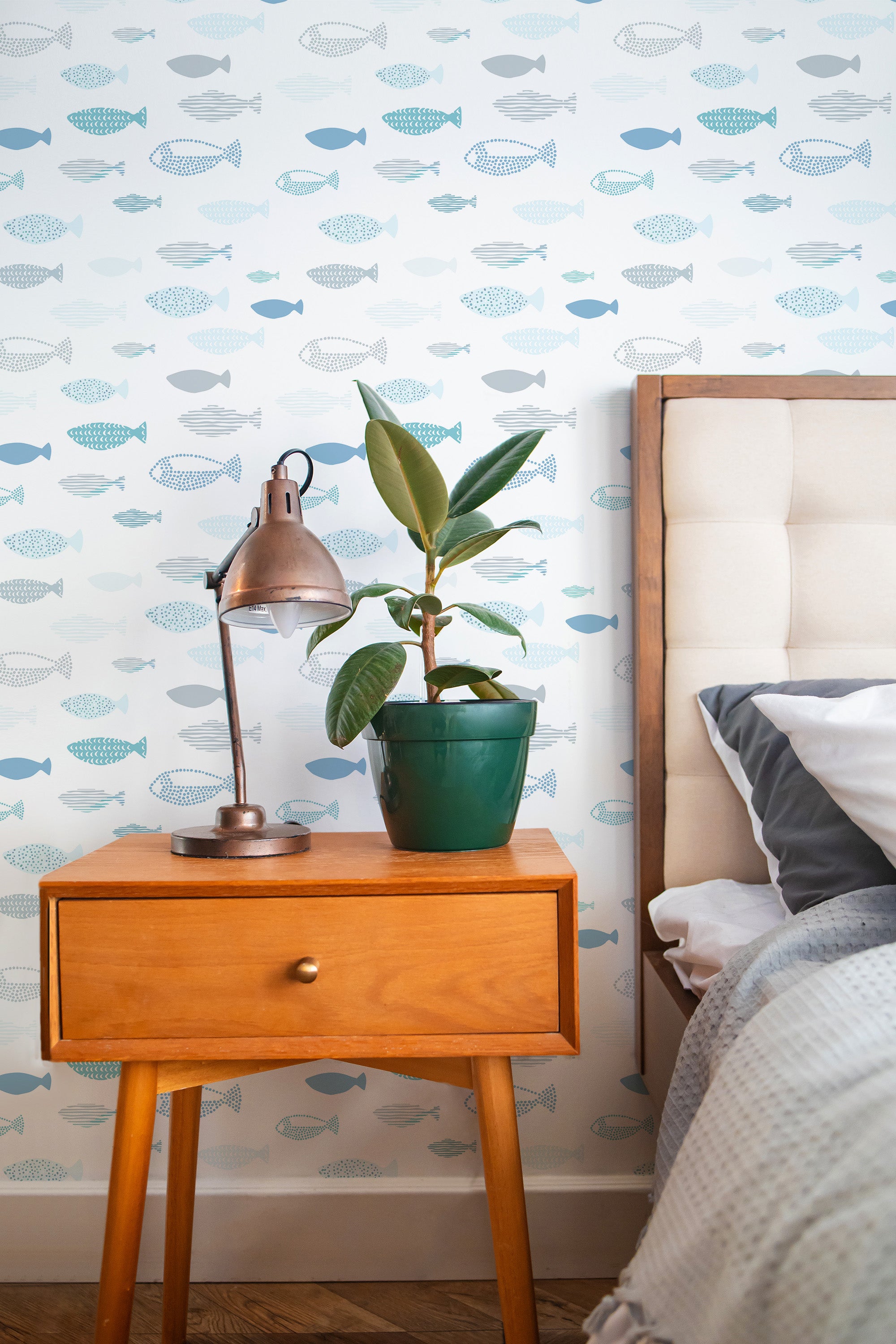 Self-adhesive wallpaper with a whimsical pattern of various fish in shades of blue, gray, and teal swimming across a white background.