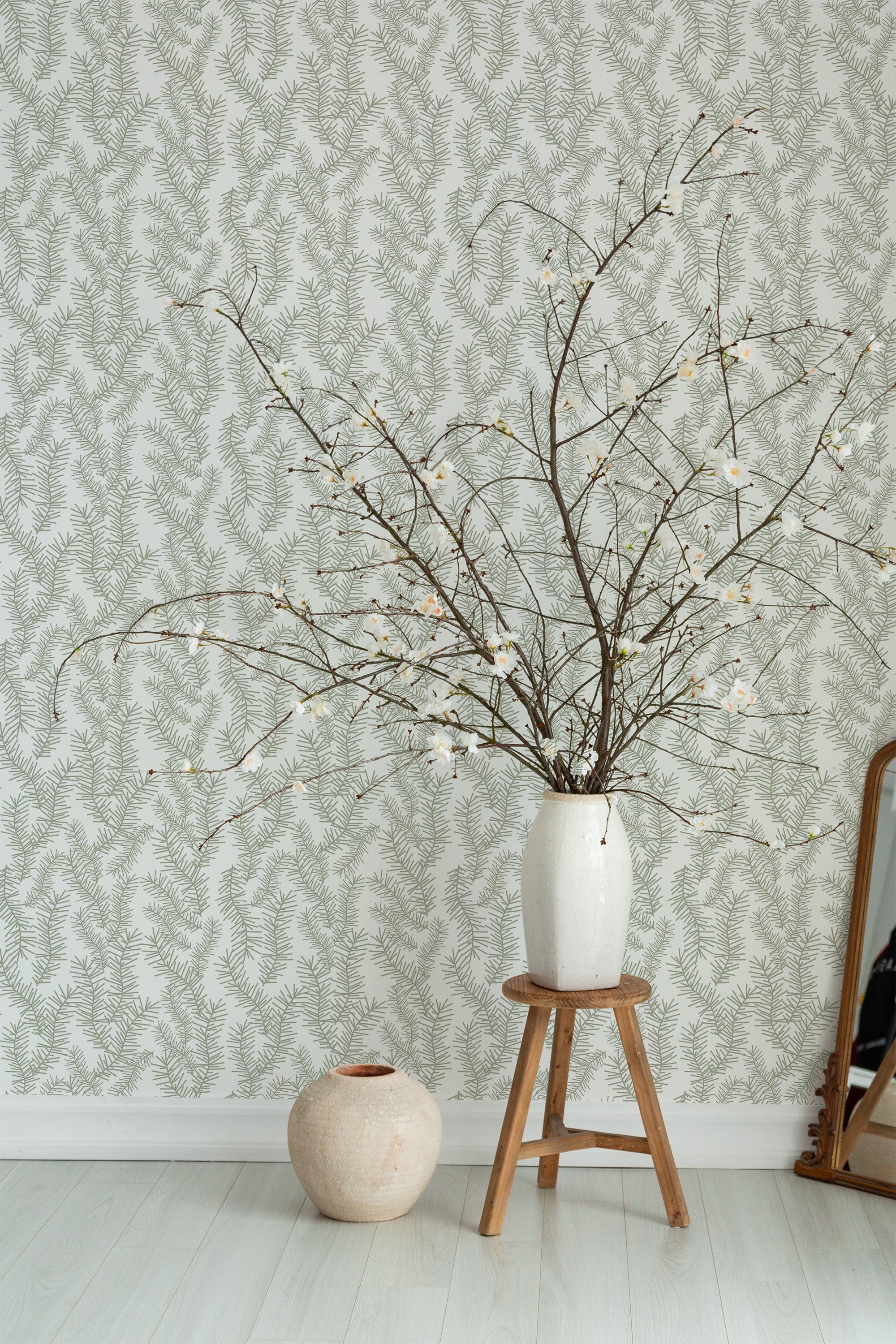 Self-adhesive wallpaper with a delicate pine tree branches design in muted green tones on a soft white background.