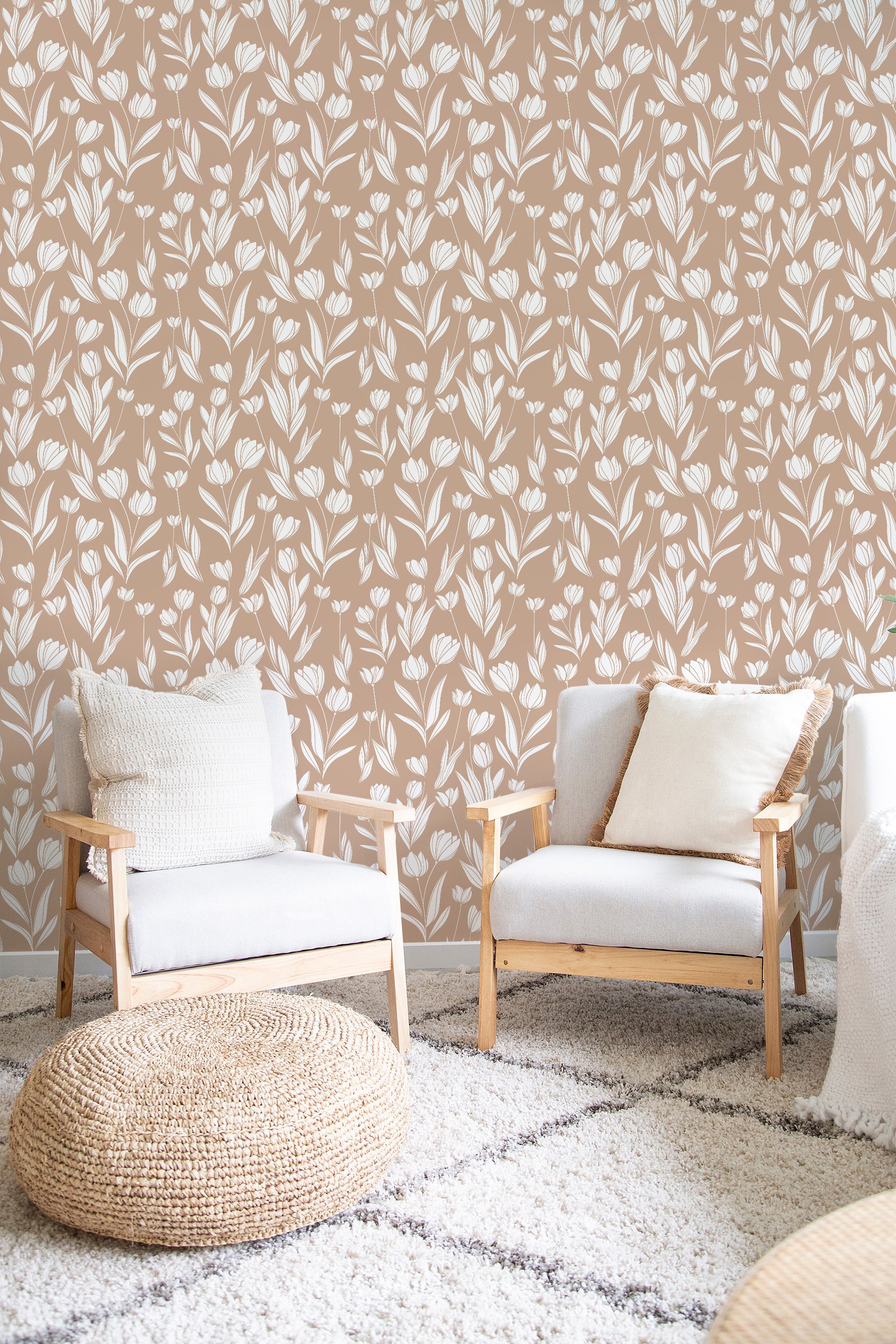 Two light-colored chairs are set in front of a wall adorned with beige and white floral wallpaper, featuring delicate tulip patterns and leafy vines spread evenly across the surface, creating an elegant and calming atmosphere. The design creates a soft, timeless aesthetic, typical of traditional wallpaper.