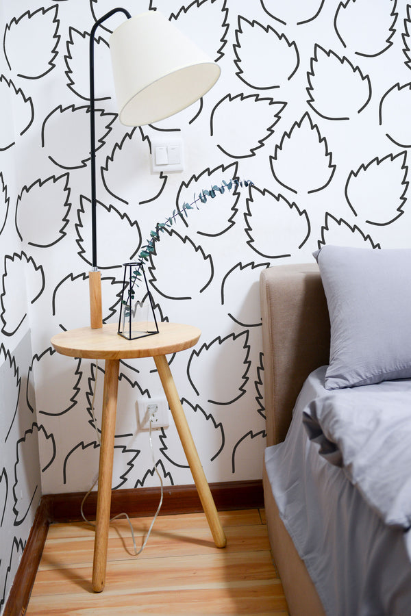 Self-adhesive wallpaper with a minimal leaf design using simple black line art on a white background, providing a clean and modern aesthetic to the room.