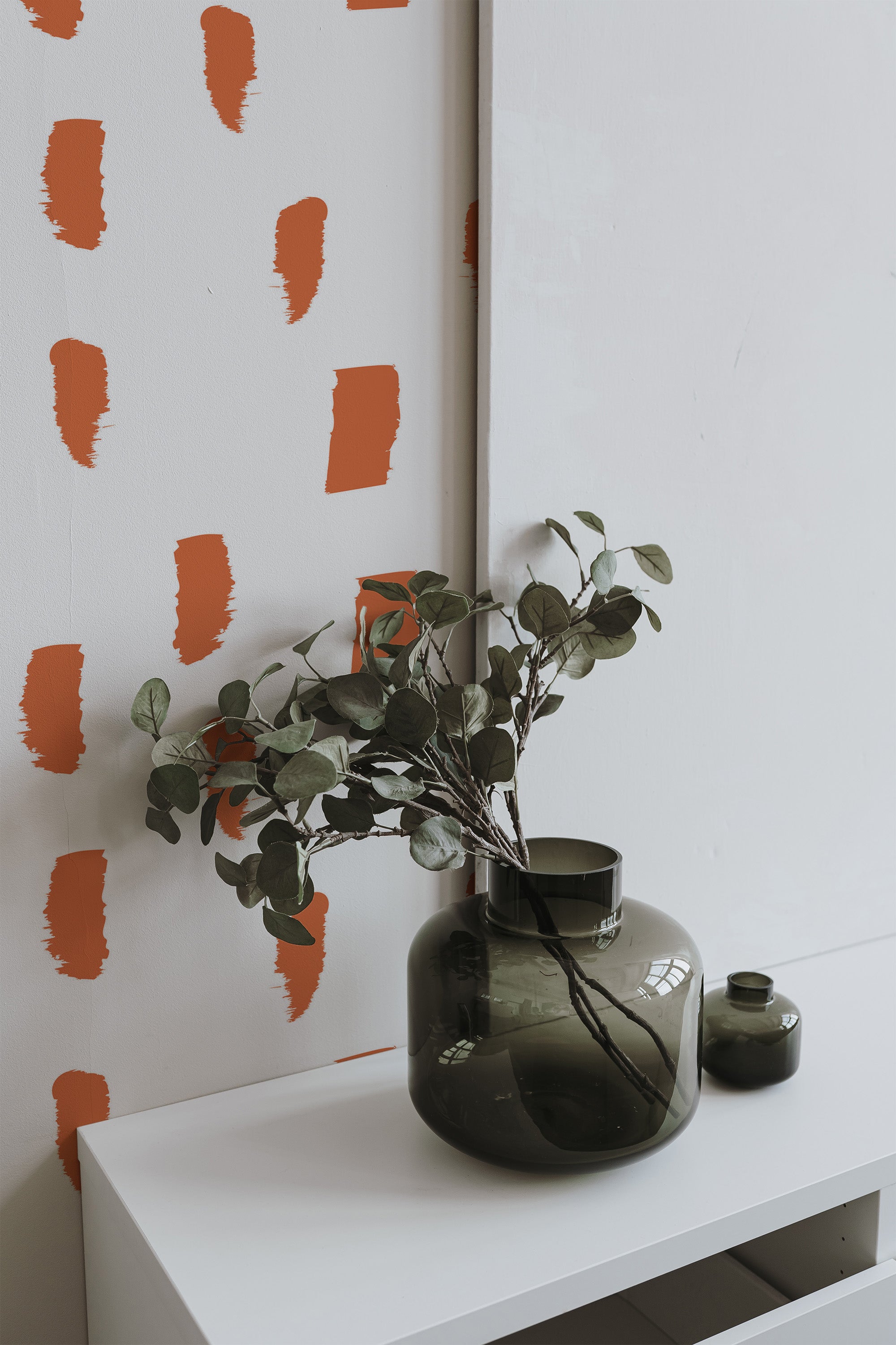Self-adhesive wallpaper with an abstract painted dots print, featuring bold orange brushstroke-like marks on a white background.