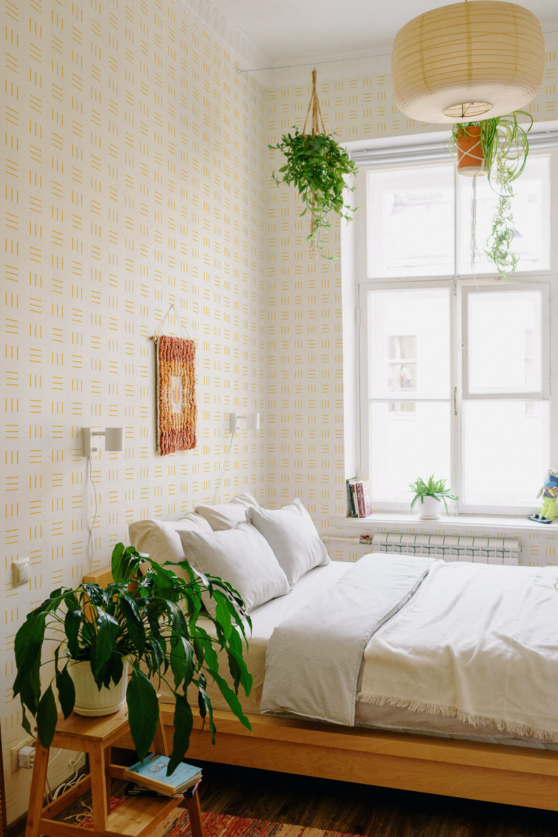 A room with light-colored wallpaper adorned with a symmetrical pattern of evenly spaced horizontal and vertical lines in yellow, creating a subtle grid-like design. Traditional wallpaper.