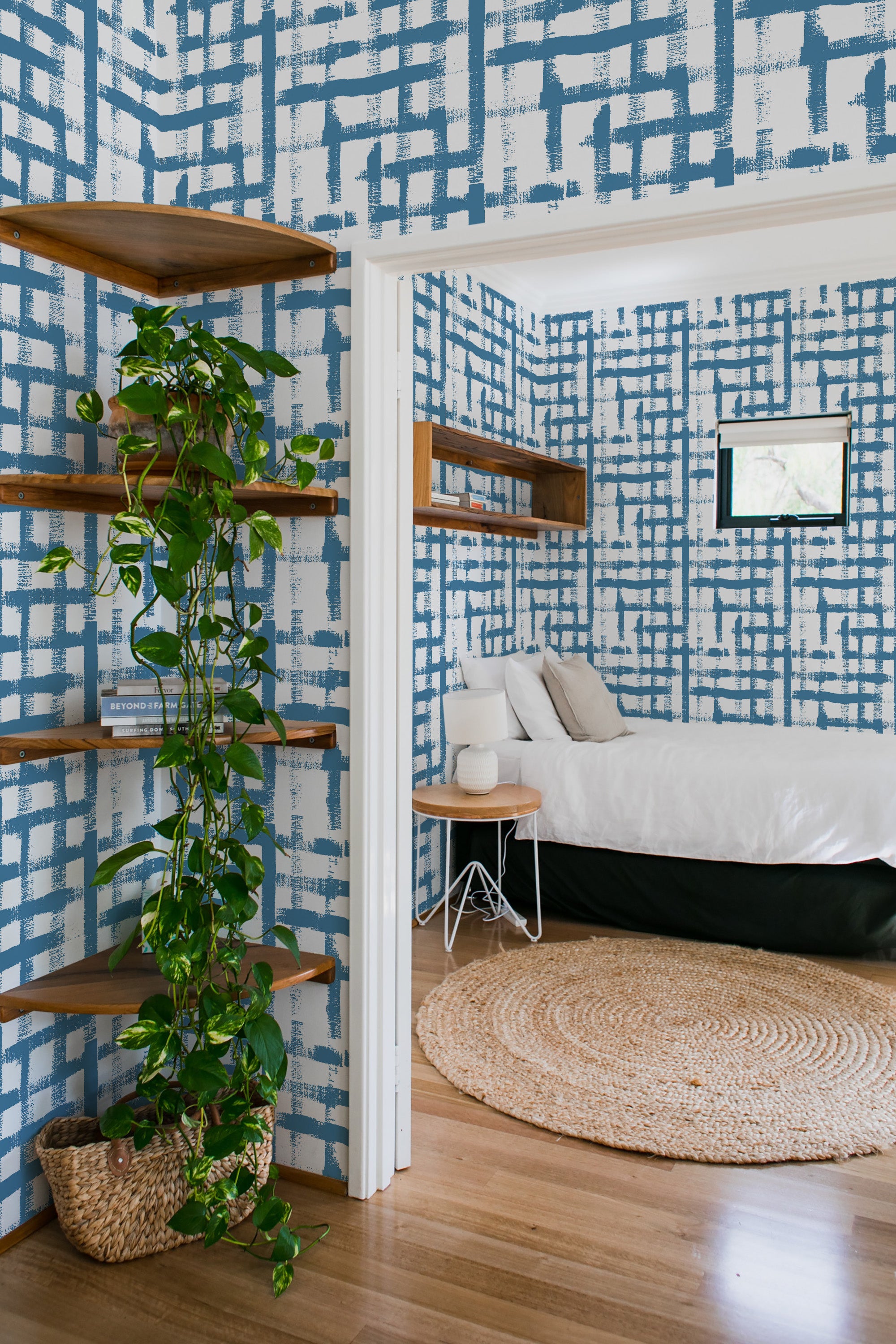 Blue and white grid-patterned wallpaper with varying line thicknesses and brushstroke textures covers the walls of a cozy room, creating a classic and elegant look. Traditional wallpaper.