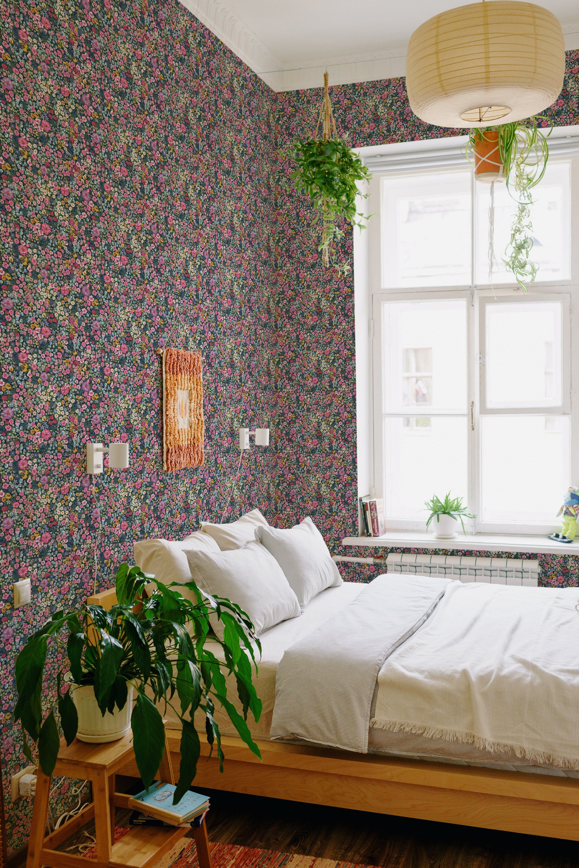 A room with wallpaper in a colorful bold floral pattern covering the walls. The design includes an array of small, vibrant flowers in shades of pink, purple, green, and blue against a dark background, creating a lively and traditional wallpaper.